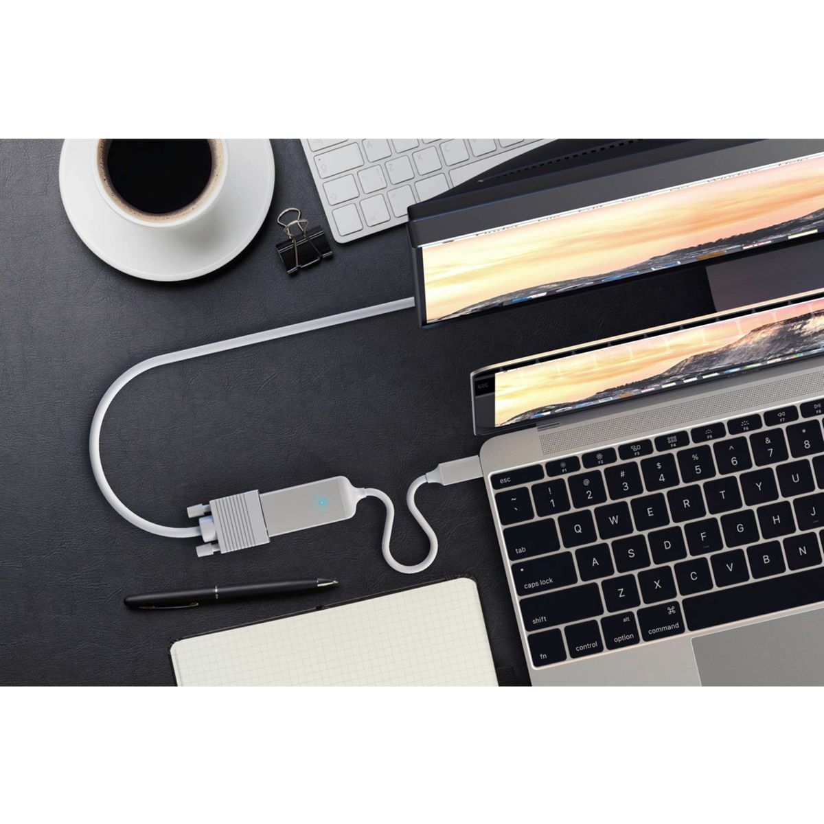 Laptop, der über ein weißes Kabel mit einem Monitor verbunden ist, und ein Stift.
