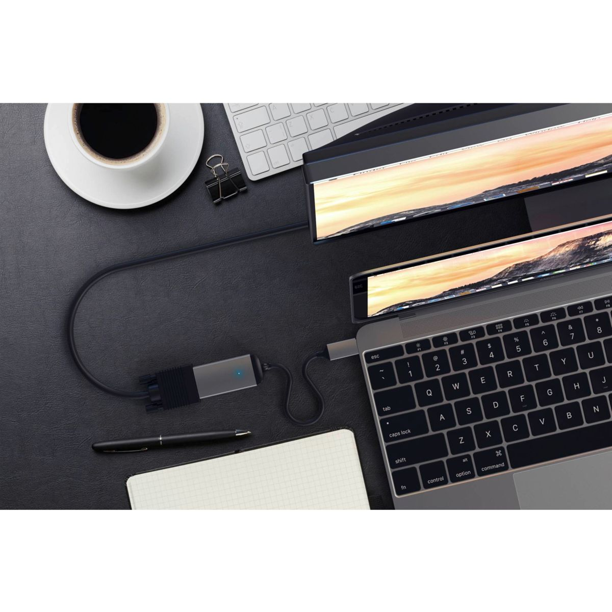 Laptop mit Monitor, Tastatur, Kaffeetasse und Stift auf einem schwarzen Schreibtisch.