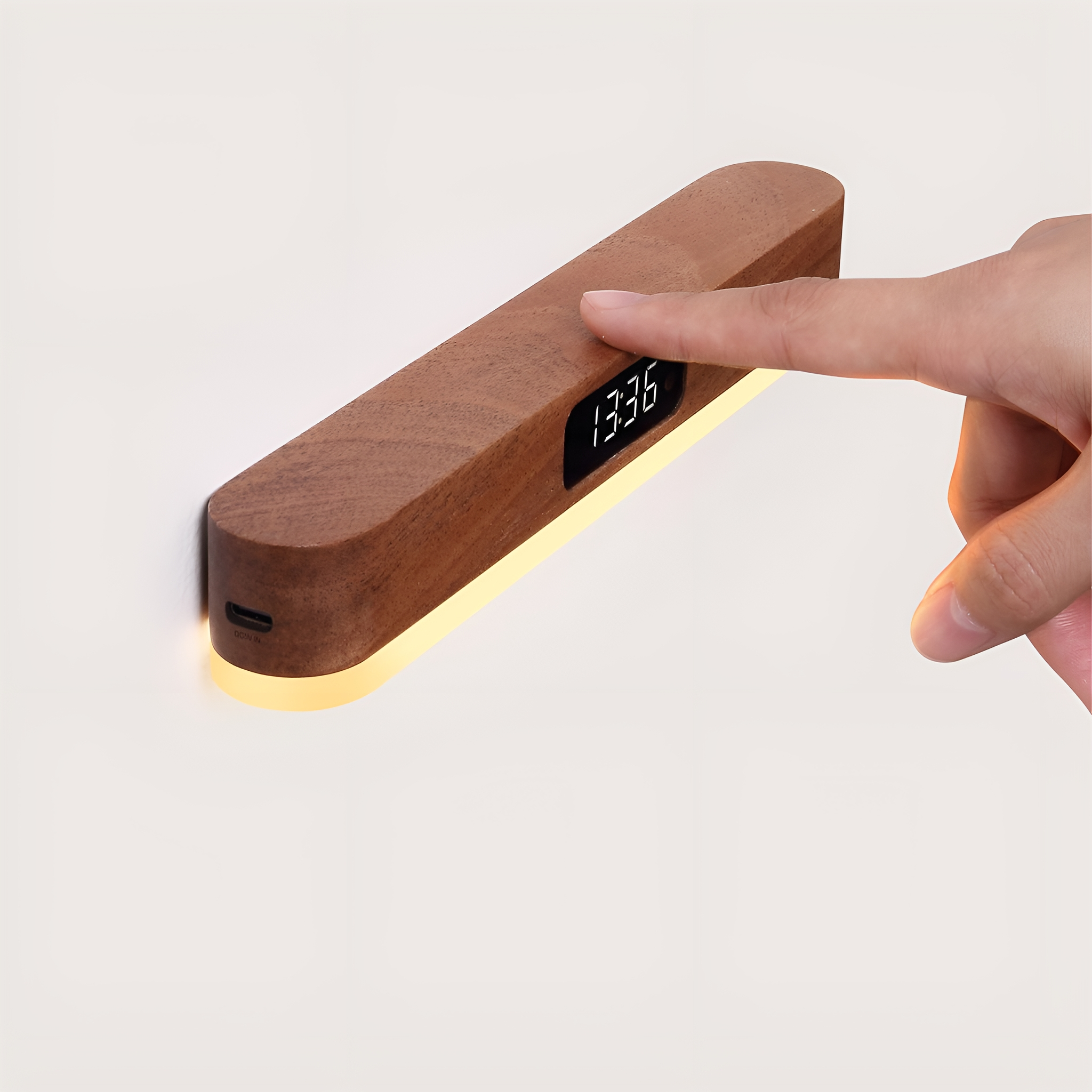 Eine hölzerne Nachttischlampe, die die Uhrzeit anzeigt, mit einer Hand, die sie berührt.