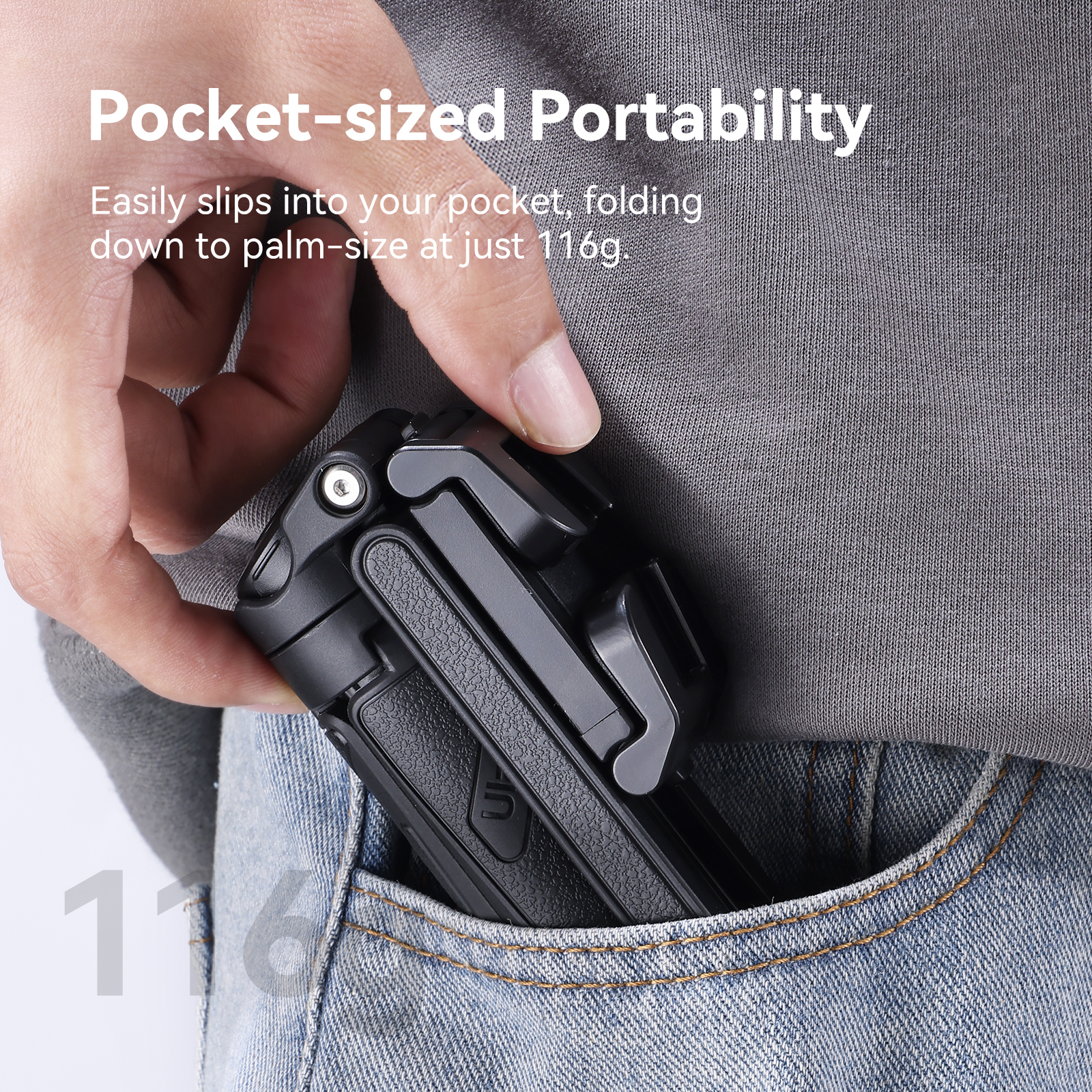 A folded black tripod being placed into a pocket by hand.