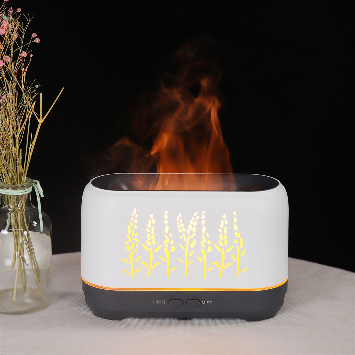 Ein weißer Diffusor mit orangenen Flammen, Blumendesign und 'Light'- und 'Mist'-Tasten auf schwarzem Hintergrund.