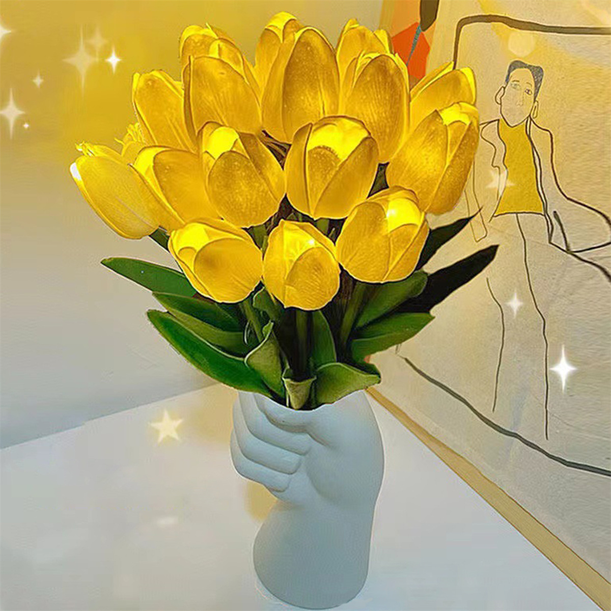 Ein Strauß gelber Tulpen in einer handförmigen Vase, auf einer weißen Oberfläche.