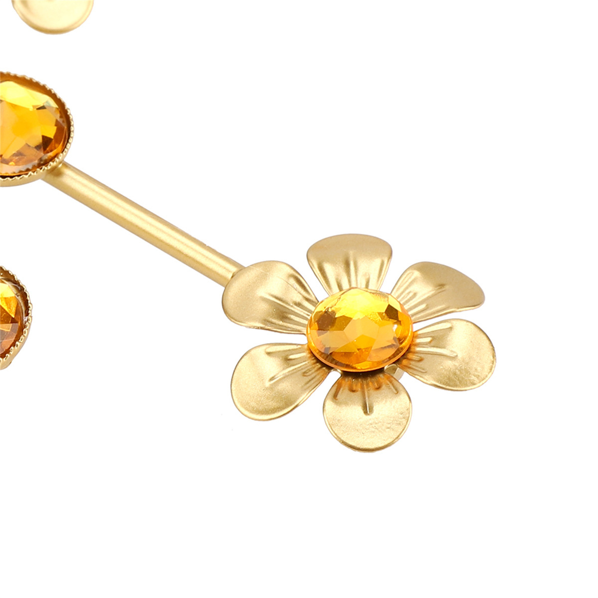 Eine goldfarbene, stilisierte Blume mit einem großen gelben Edelstein in der Mitte.