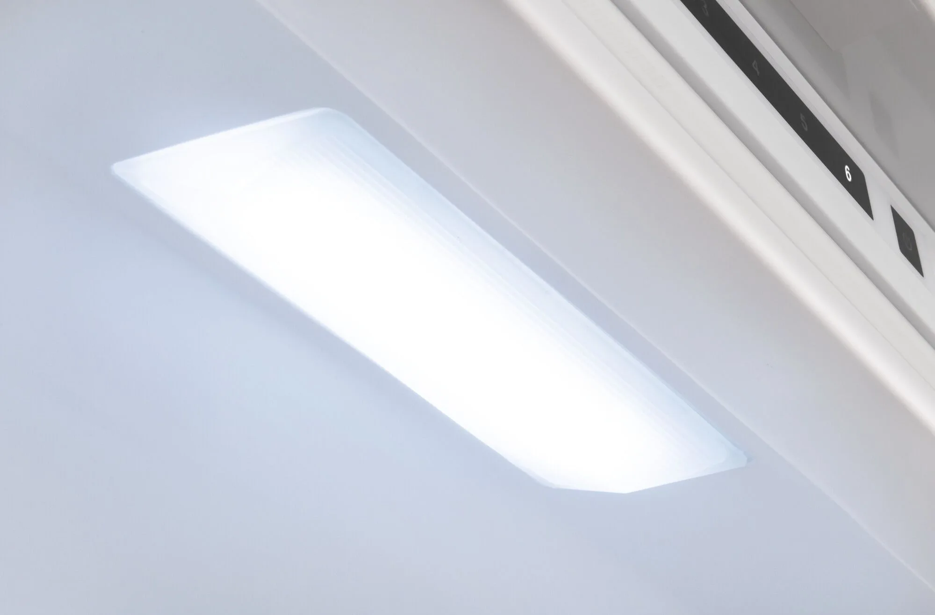 Primer plano de una lámpara dentro de un refrigerador, emitiendo una luz blanca brillante.