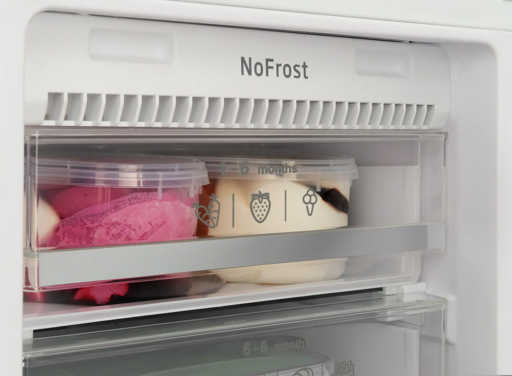 Dentro de una nevera, contenedores transparentes con contenido rosa y blanco, etiquetados '6 meses'.