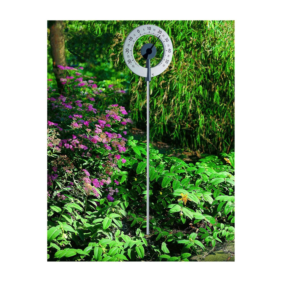 Eine Wetterstation in einem Garten, mit einem kreisförmigen Zifferblatt und einer langen Metallstange.