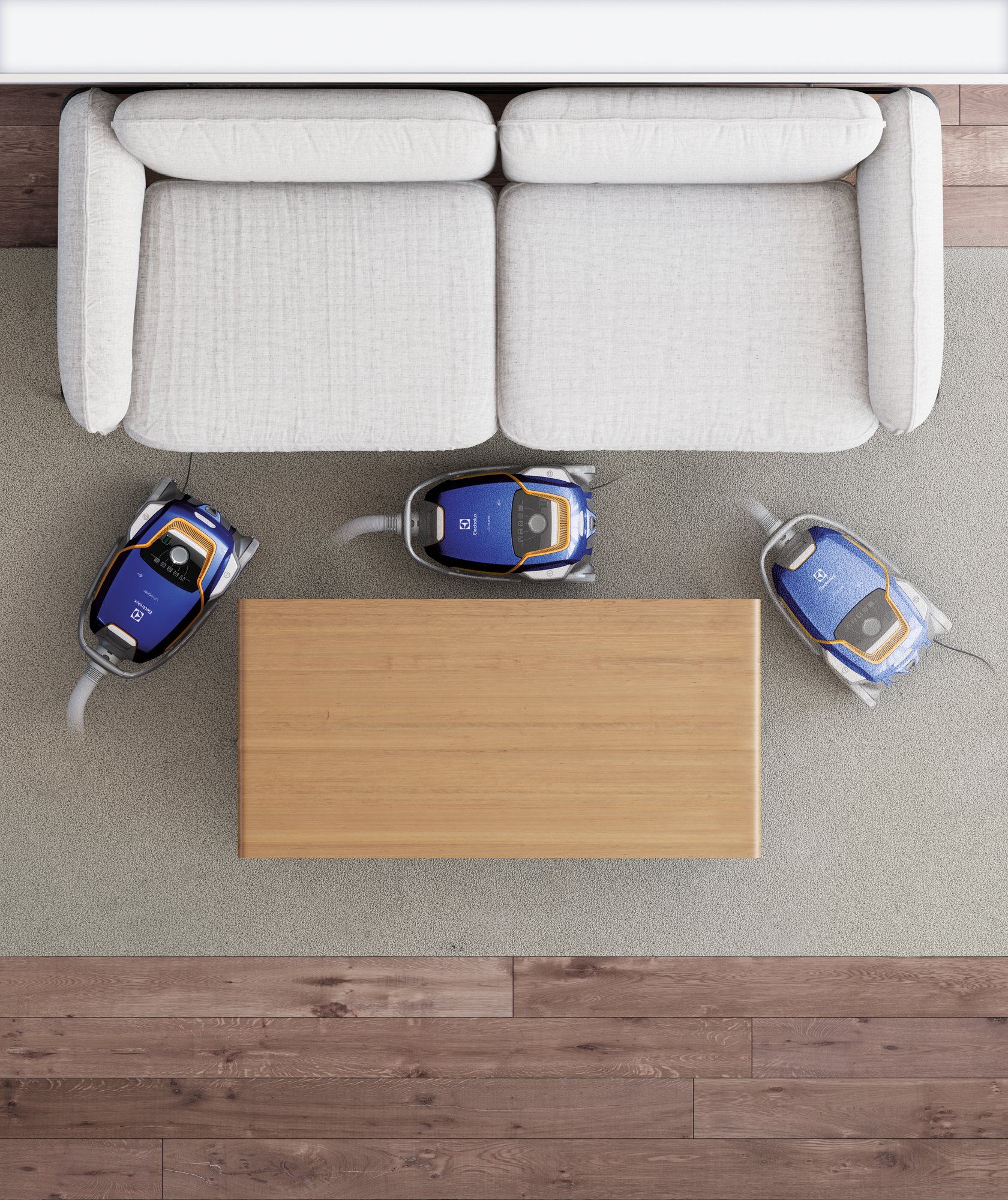 Trzy odkurzacze obok drewnianego stołu i białej kanapy na jasnobrązowym dywanie.