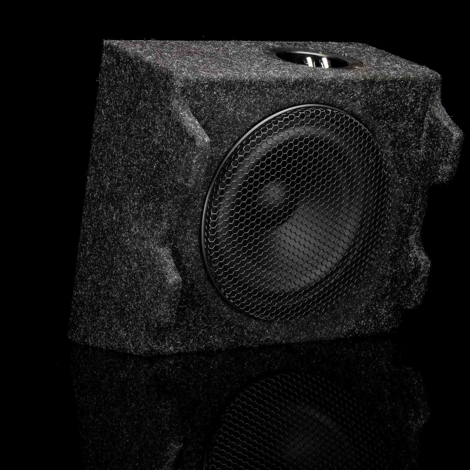 Eine schwarze Lautsprecherbox mit Mesh-Front vor schwarzer, reflektierender Oberfläche.