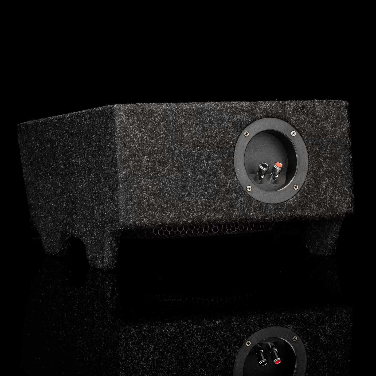 Schwarze, rechteckige Subwoofer-Box mit strukturierter Oberfläche. Enthält einen Lautsprecher und zwei Anschlüsse.