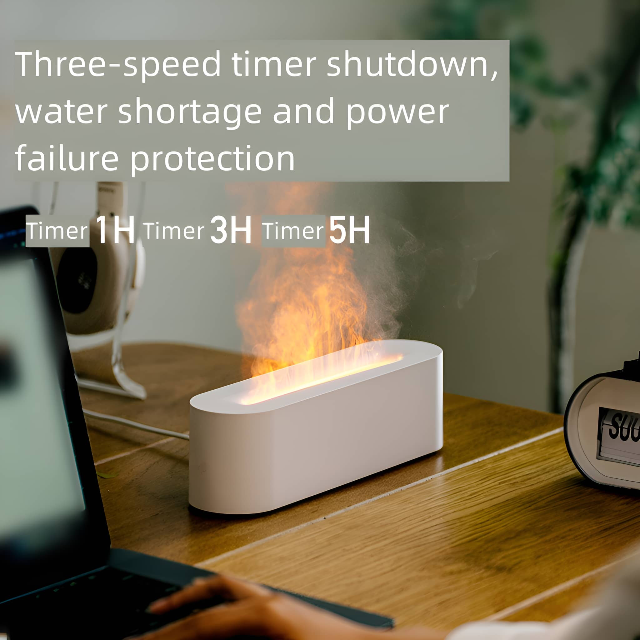 Weißes Gerät mit Flammeneffekt auf einem Tisch. Laptop und Uhr im Hintergrund.
