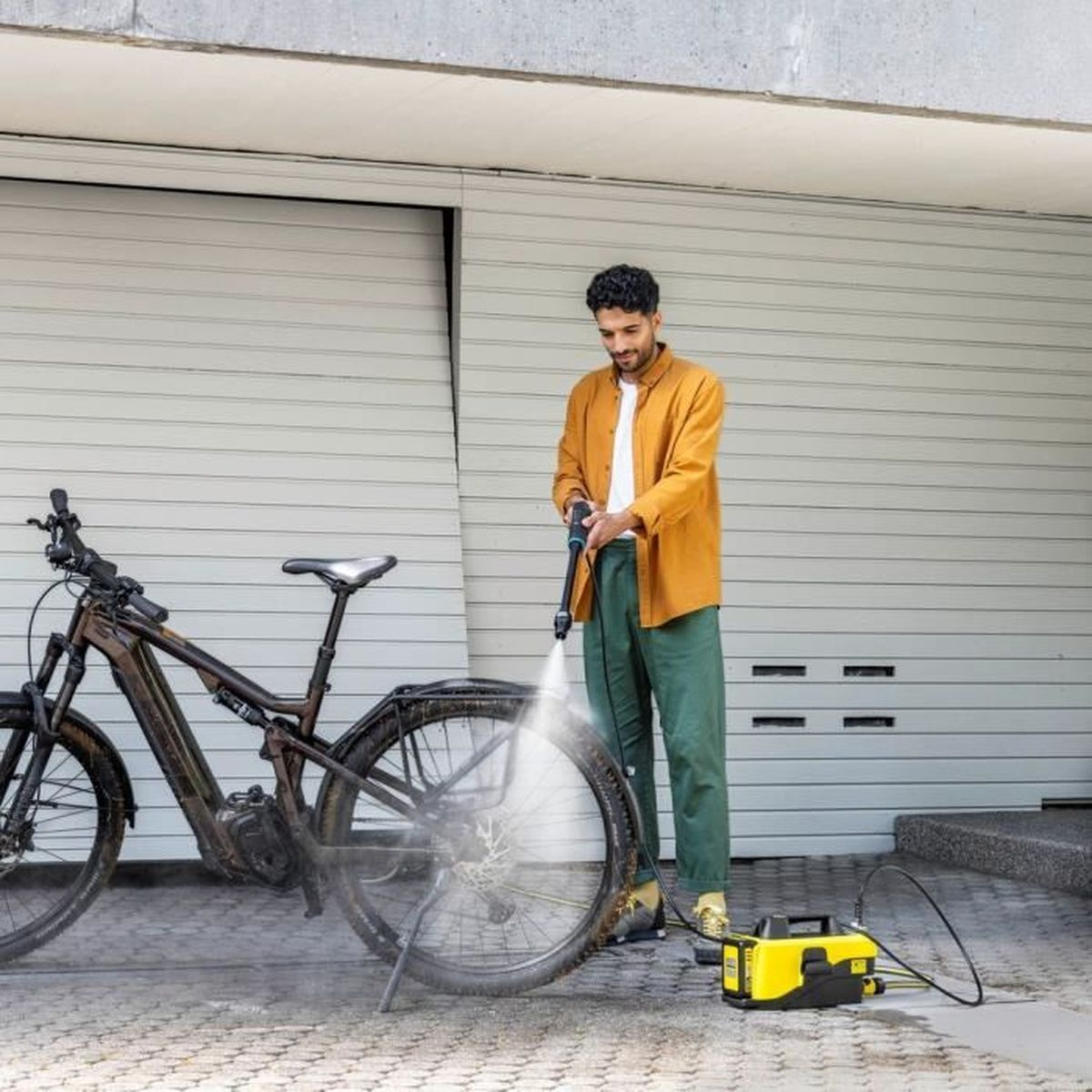 Un uomo lava una bicicletta con un'idropulitrice.