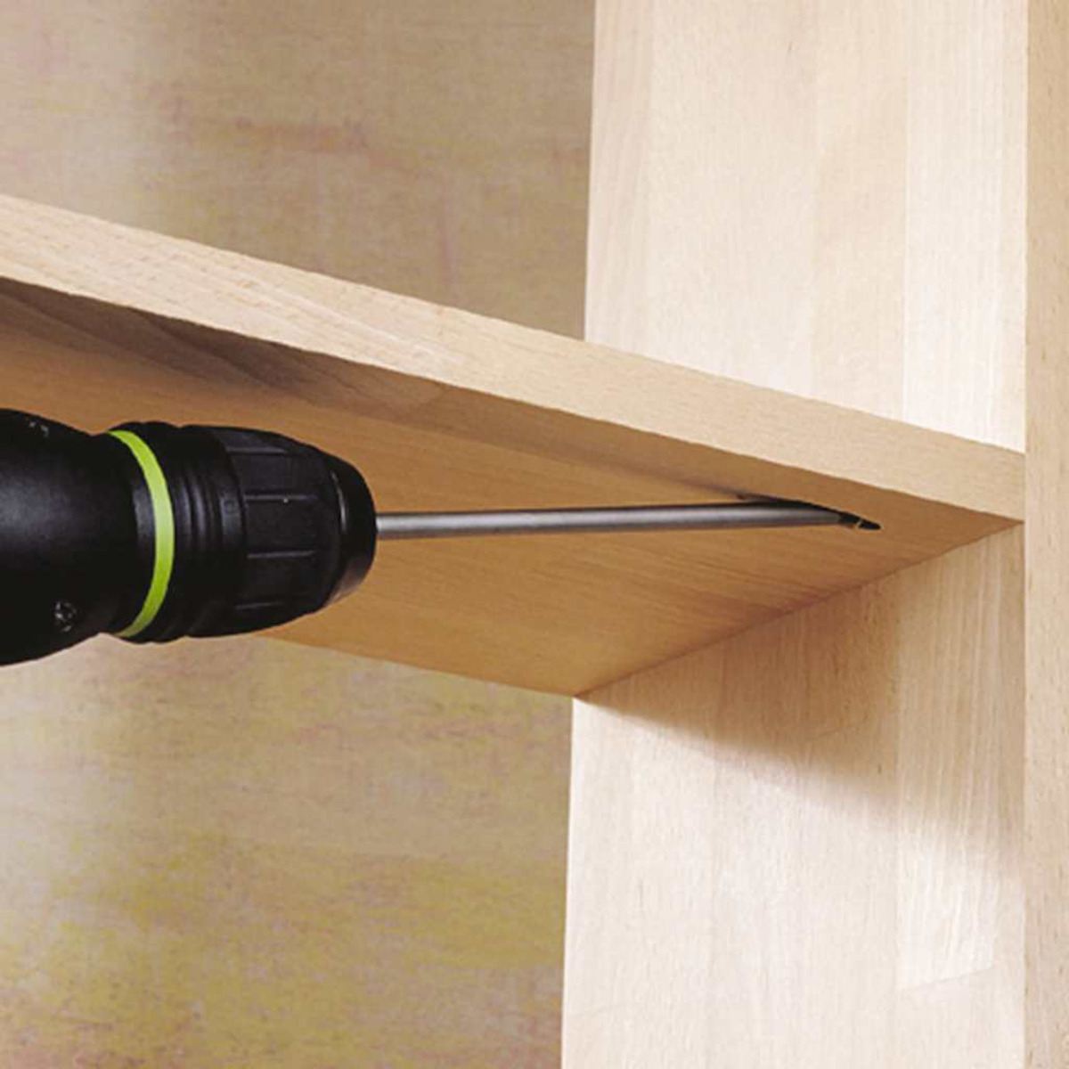 Eine Bohrmaschine, die eine Schraube in ein Holzregal treibt, Nahaufnahme der Aktion und Holzmaserung.