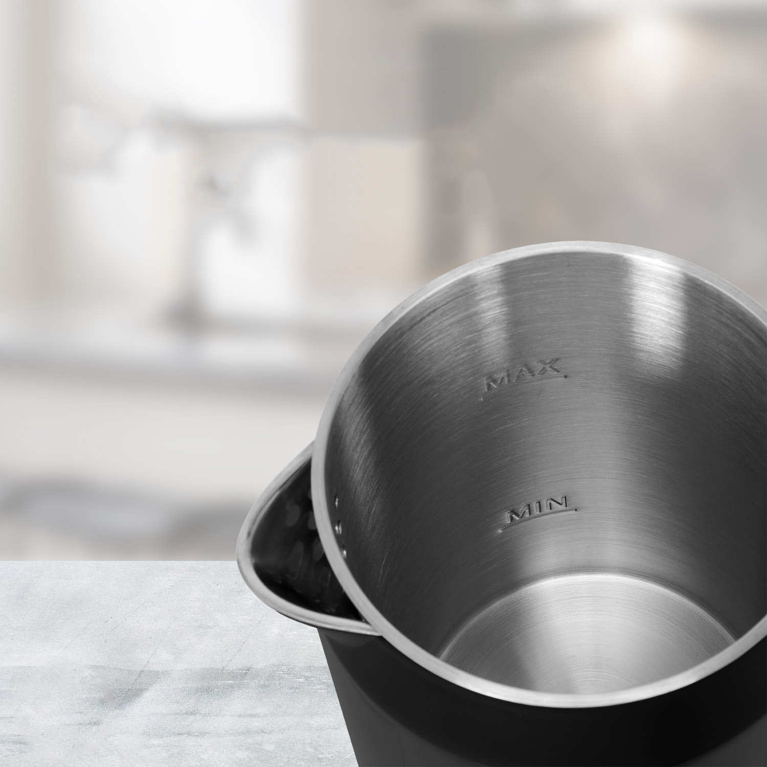 Inside view of a stainless steel kettle showing 'MAX' and 'MIN' fill lines against a blurred background.