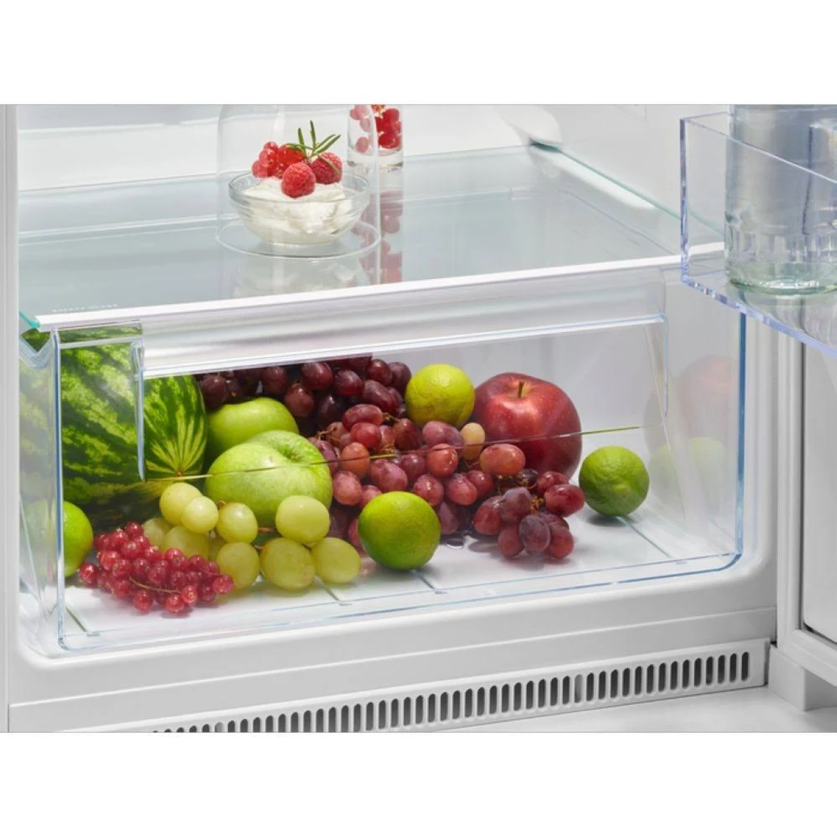 Interno di un frigorifero con frutta. Mele, uva e altra frutta.