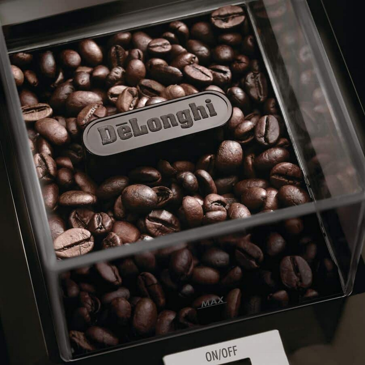Un contenedor de granos de café DeLonghi lleno de granos, primer plano, con un botón de encendido/apagado.