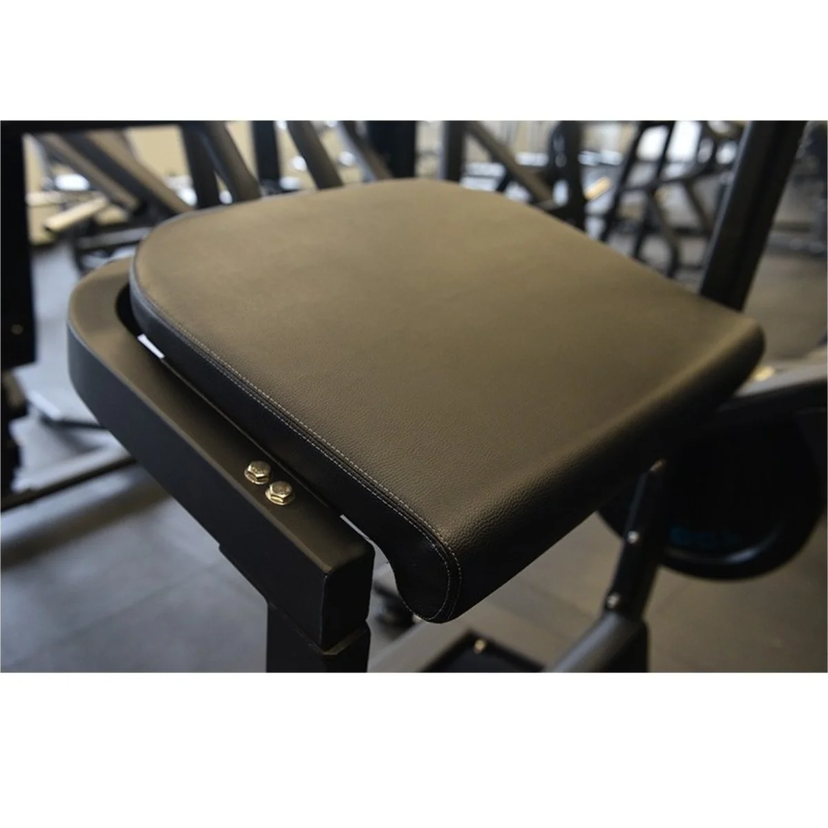 Zwart gevoerde zitting op een zwarte fitnessmachine. Metalen frame met bouten. Gymomgeving.