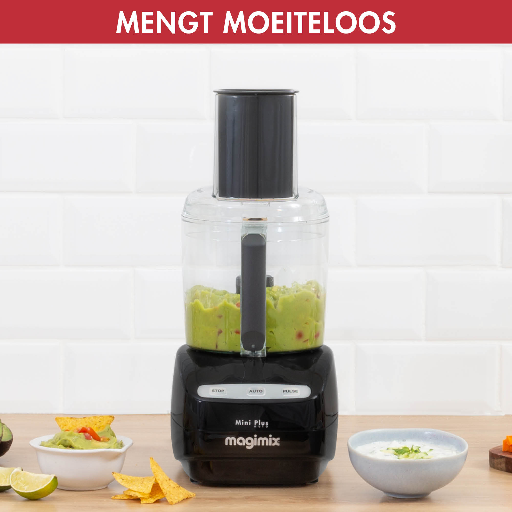 Een zwarte keukenmachine met guacamole erin, op een houten tafel.
