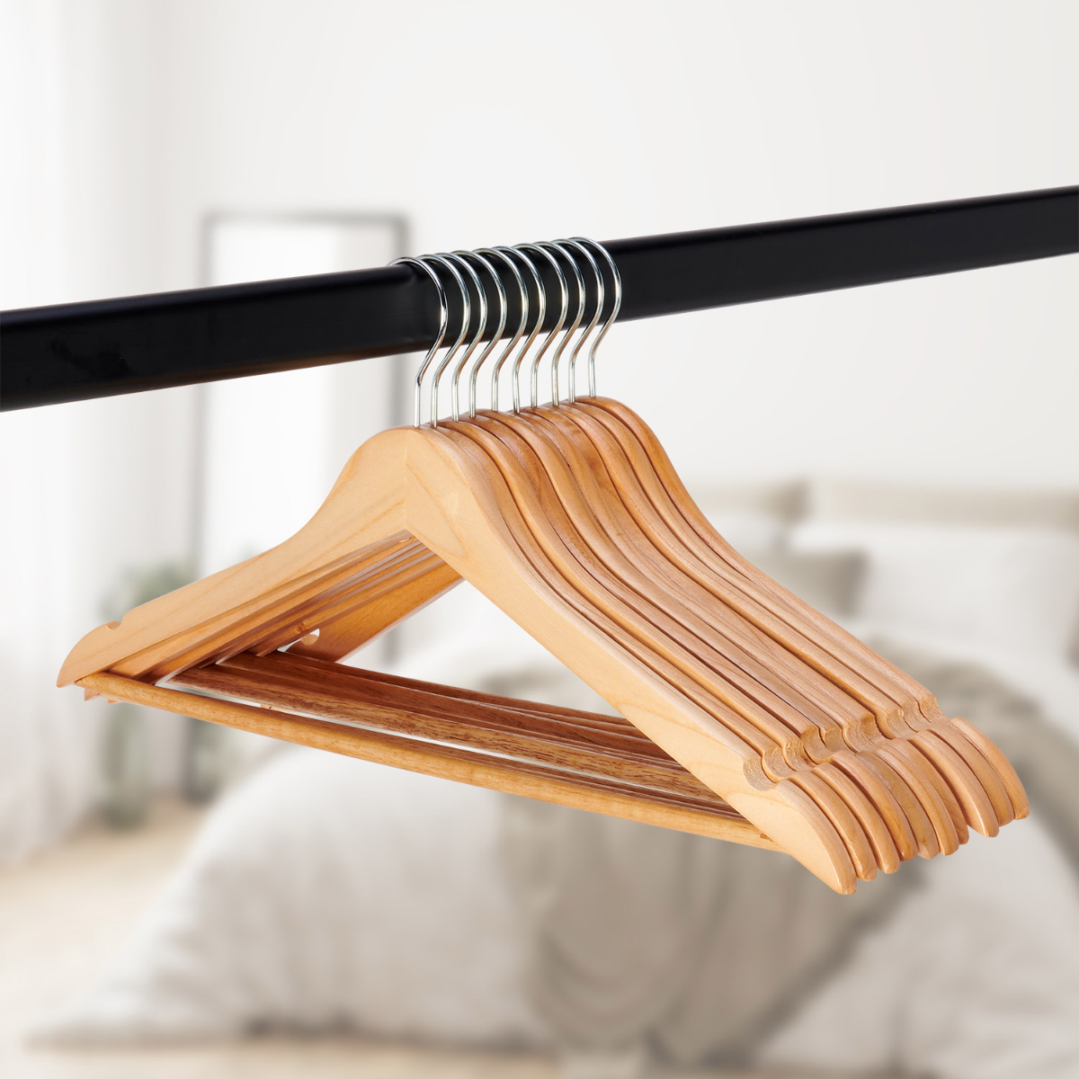 Een set houten kleerhangers aan een zwarte stang, wazige achtergrond.