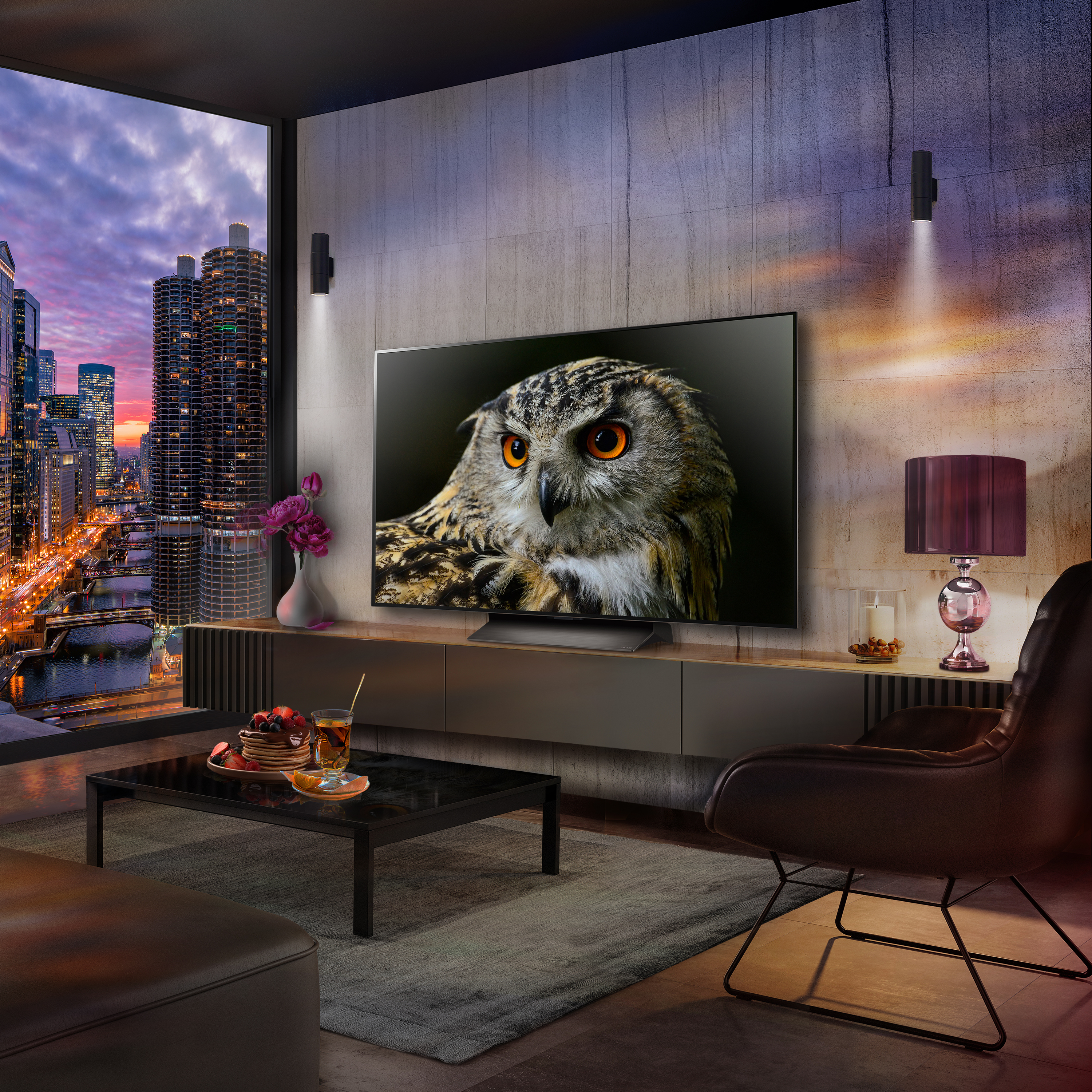 Un televisor muestra una imagen de un búho en una sala de estar moderna con vista a la ciudad de noche.