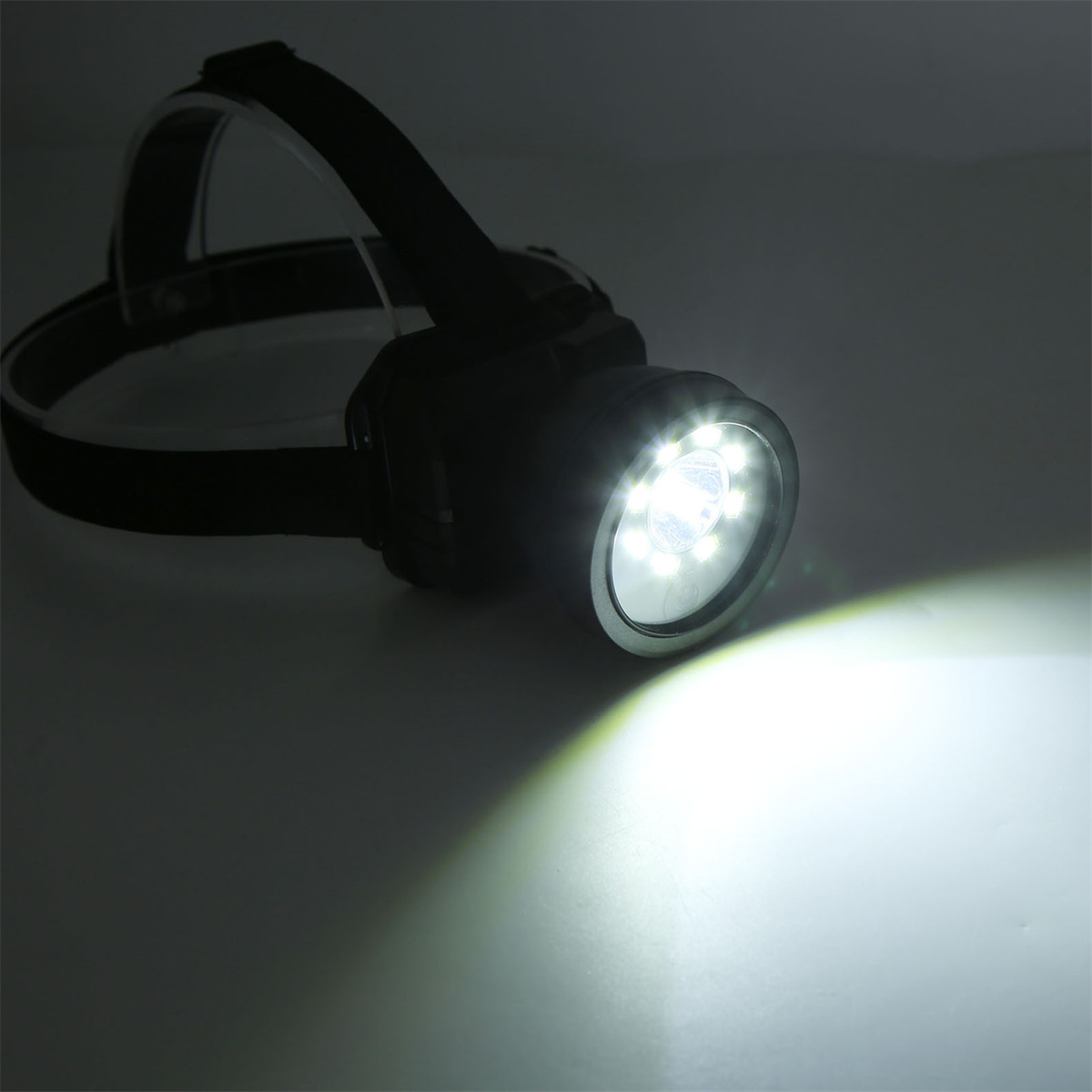 Schwarze Stirnlampe mit hellweißer LED. Der Hintergrund ist weiß.