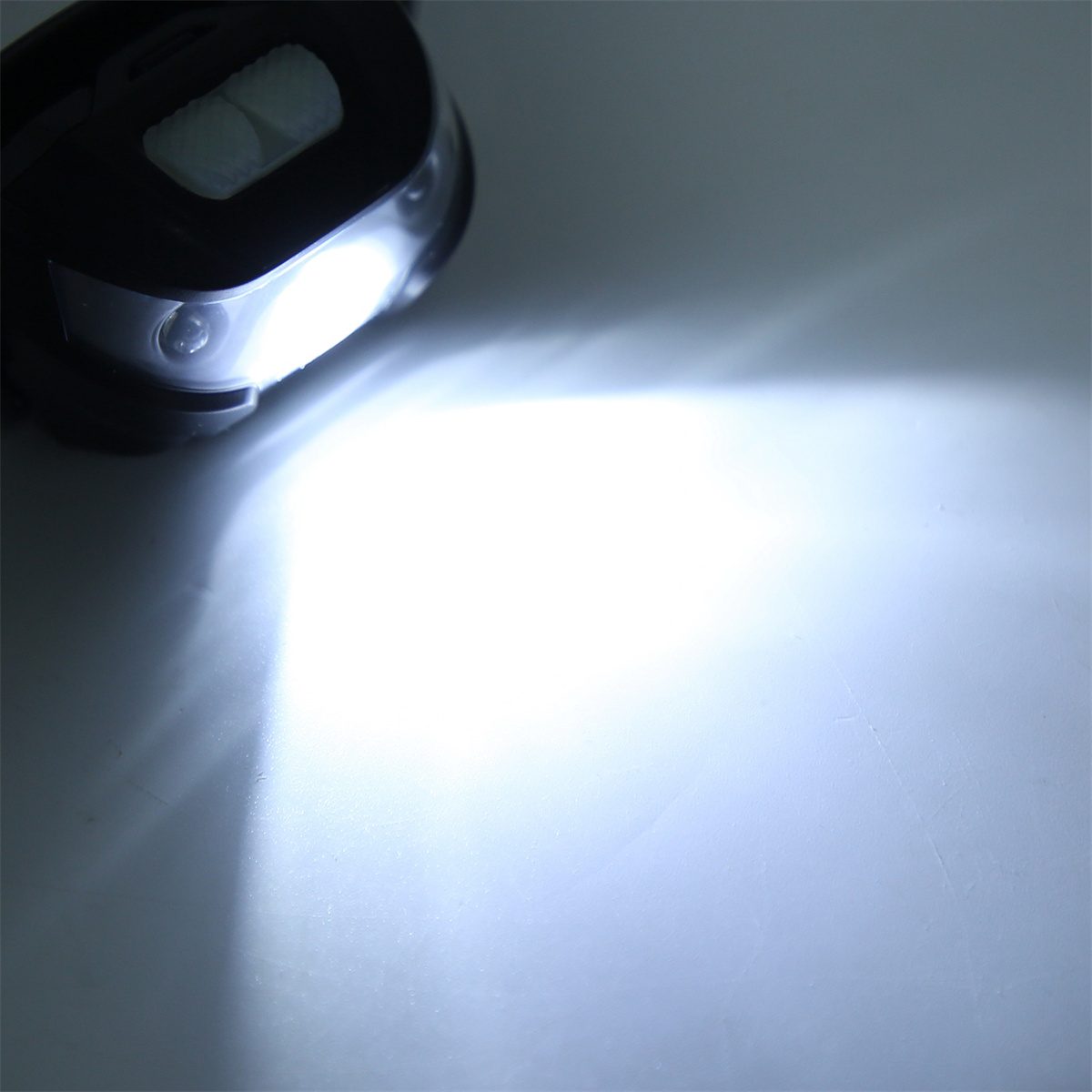 Nahaufnahme einer Taschenlampe, die helles weißes Licht auf eine weiße Oberfläche scheint. Das Licht ist fokussiert.
