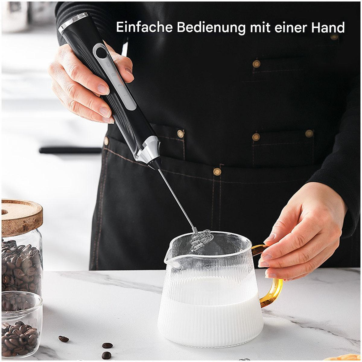 Eine Person hält einen schwarzen und silbernen Milchaufschäumer über einem Glaskrug mit Milch.
