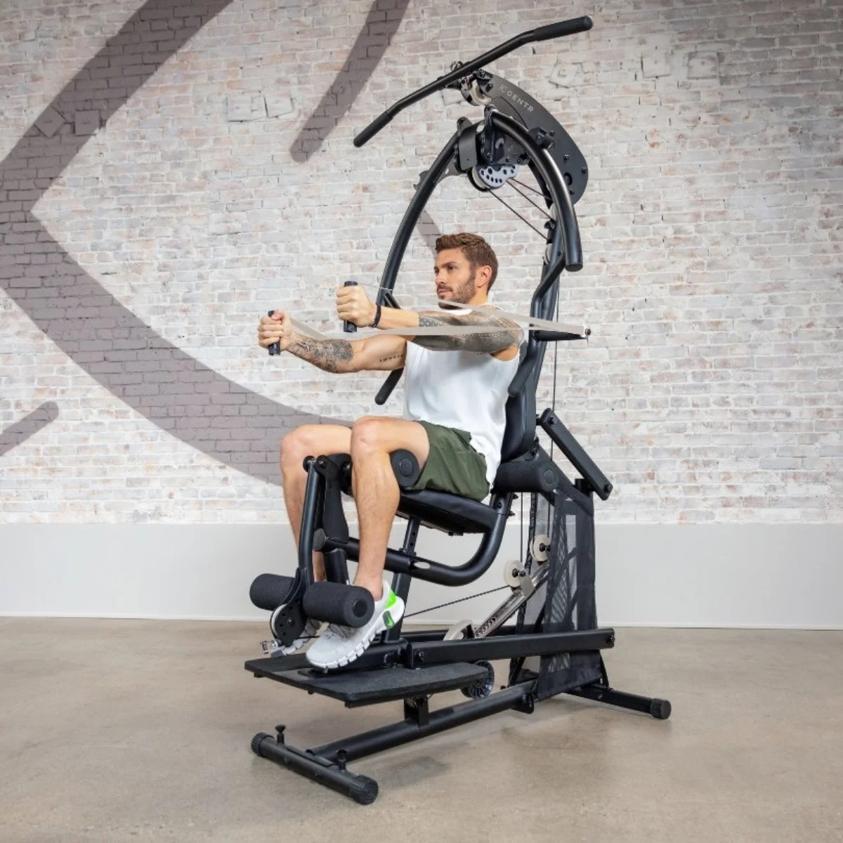 Mann benutzt sitzende Fitnessmaschine, trainiert im Fitnessstudio.