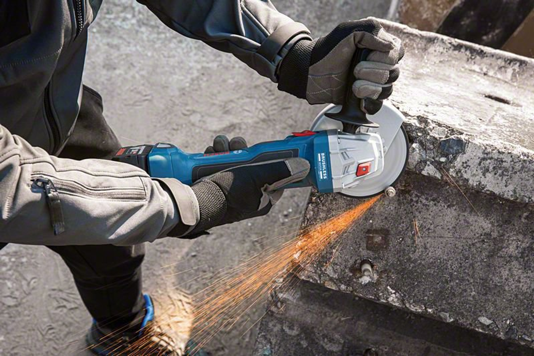 Una persona con guantes usa una amoladora para trabajar en concreto, saltan chispas.