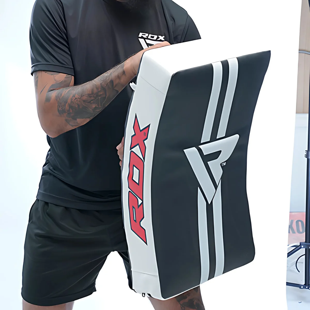 Man holding a black and white boxing shield with red ROX logo.