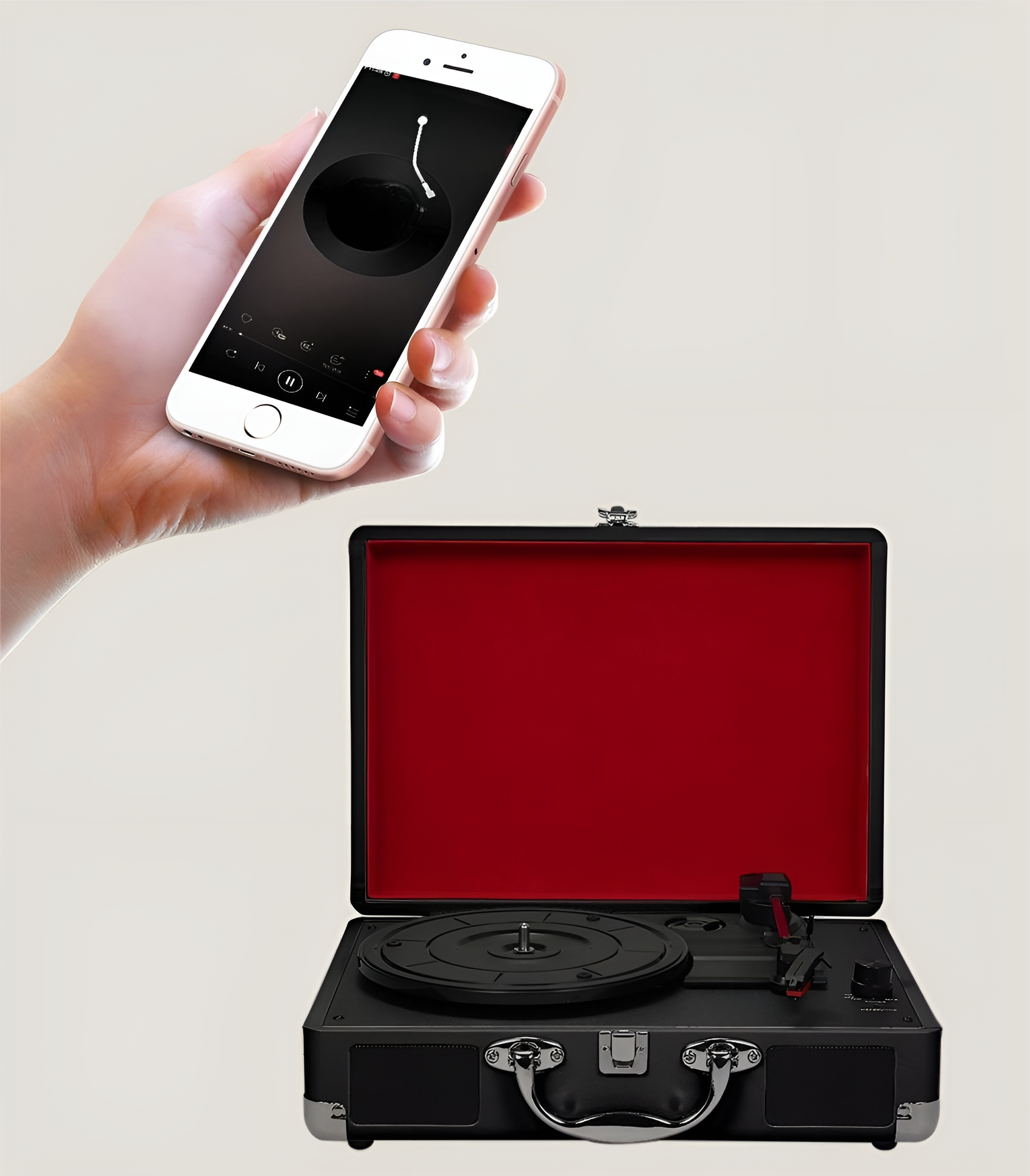 Hand hält Telefon mit Musik-Interface neben schwarzem Retro-Plattenspieler.