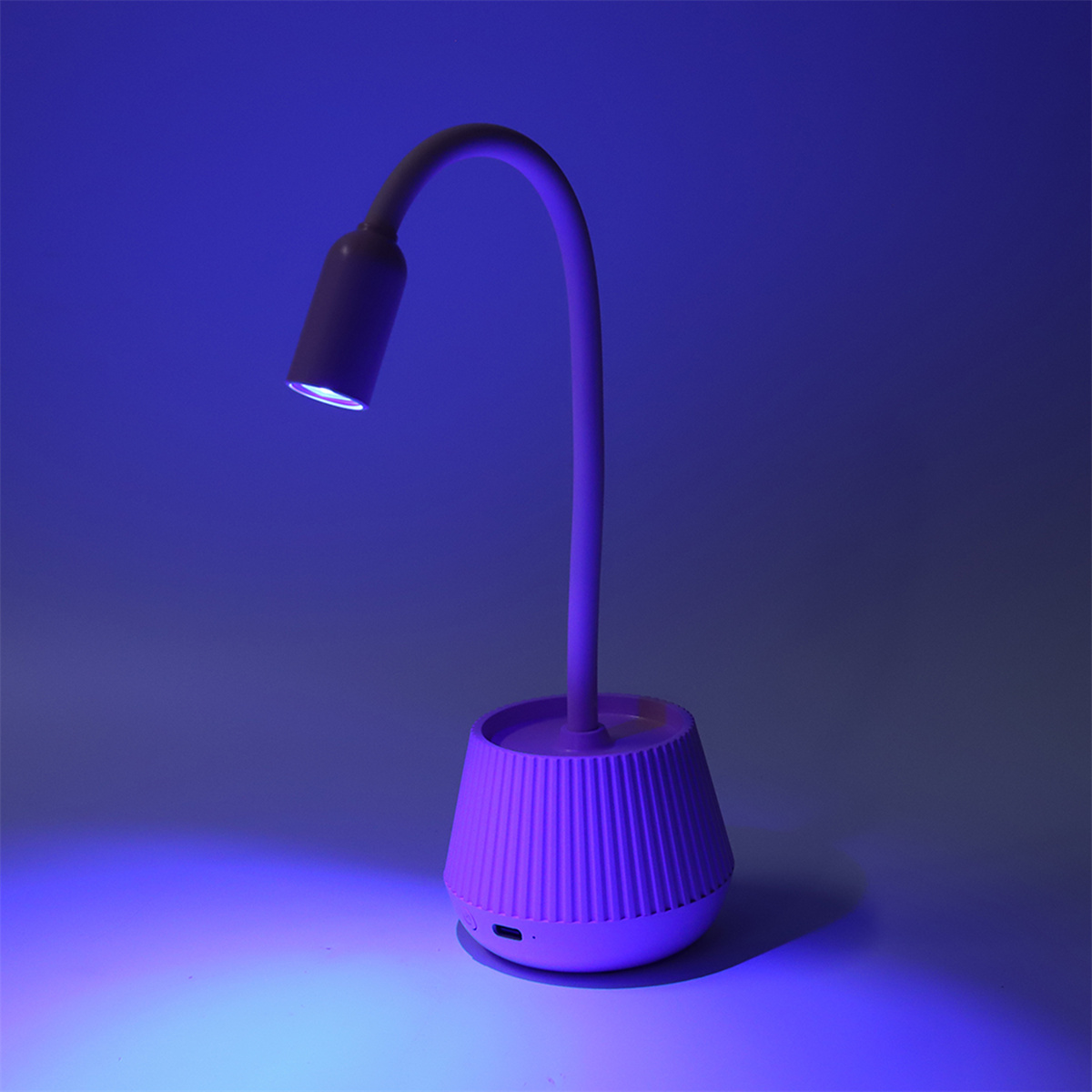 Eine pinkfarbene Schreibtischlampe mit flexiblem Hals, die ein blaues Leuchten wirft.