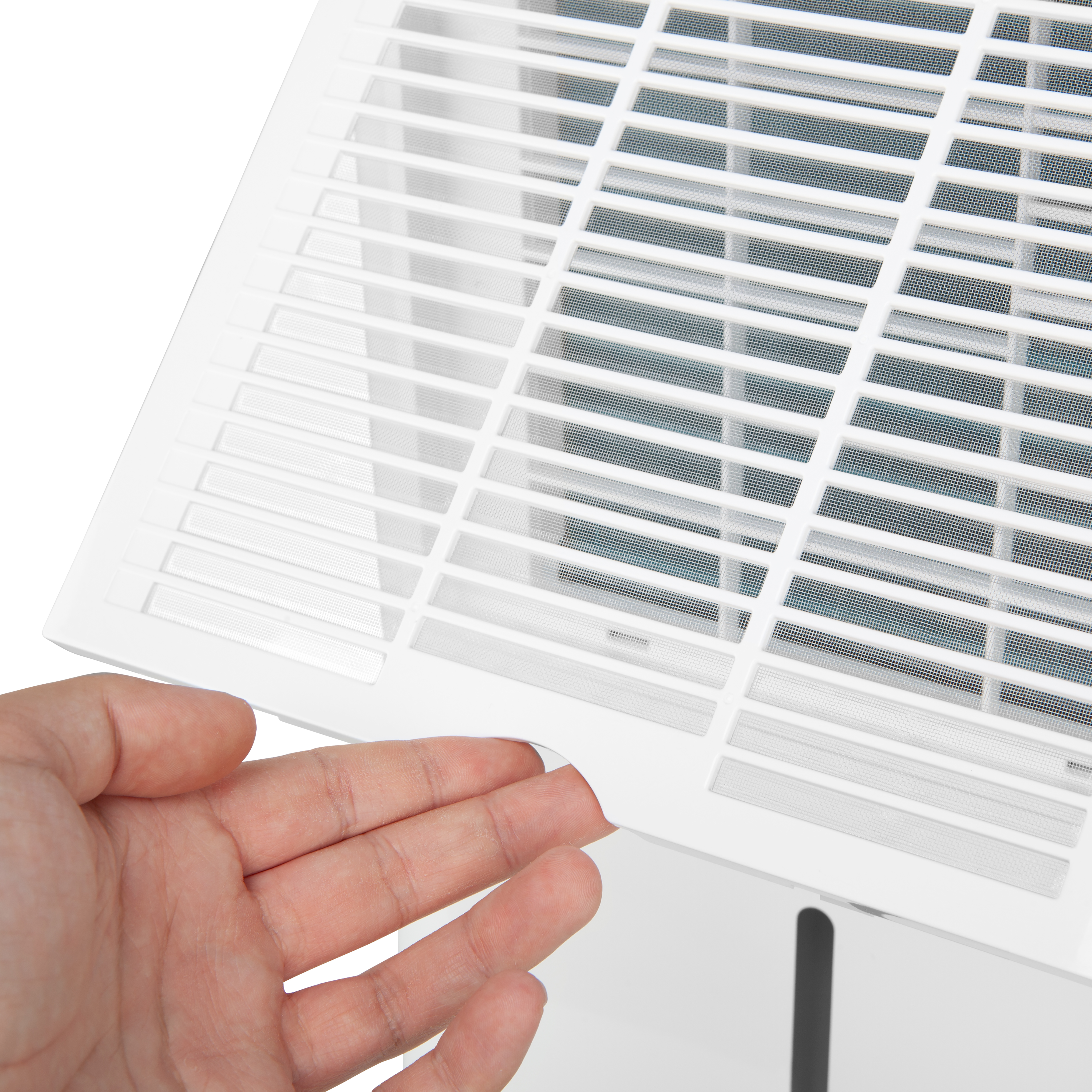 Una mano señala la ventilación blanca de un dispositivo. La ventilación tiene un patrón de rejilla.