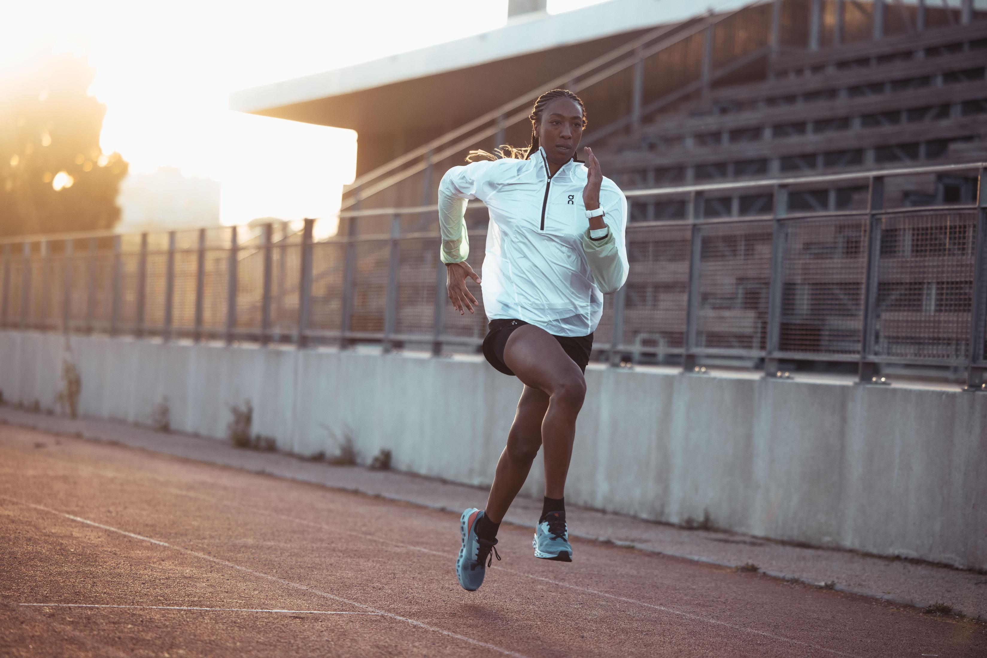 Kobieta biegnąca po torze, ubrana w strój sportowy i zegarek.