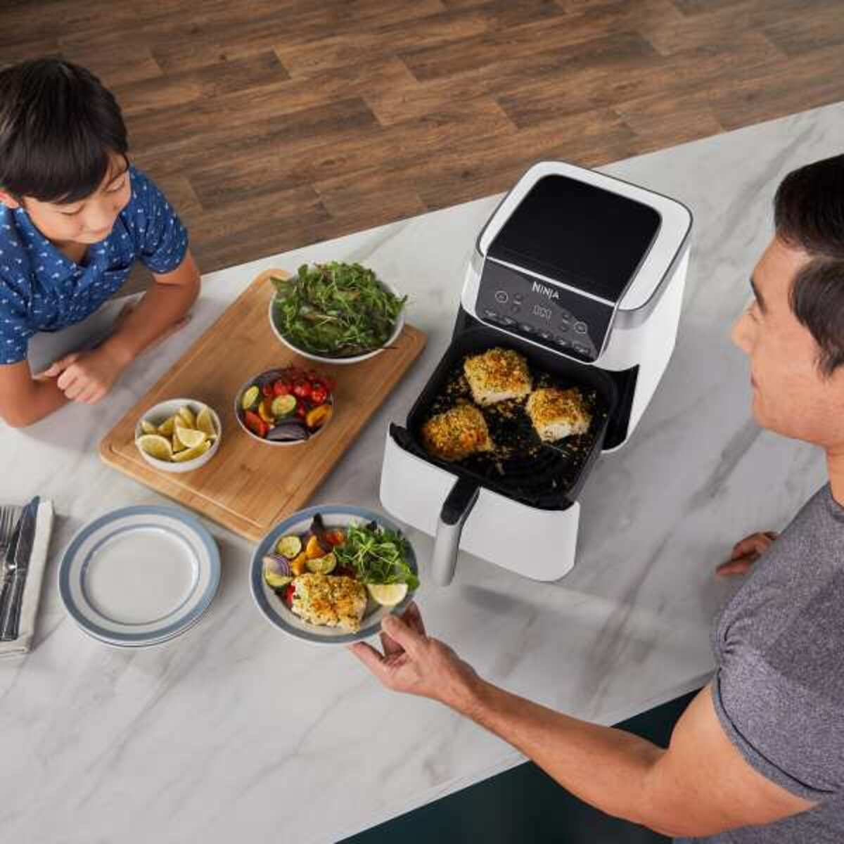 Osoba trzyma talerz z ugotowanym jedzeniem. Druga osoba na to patrzy.