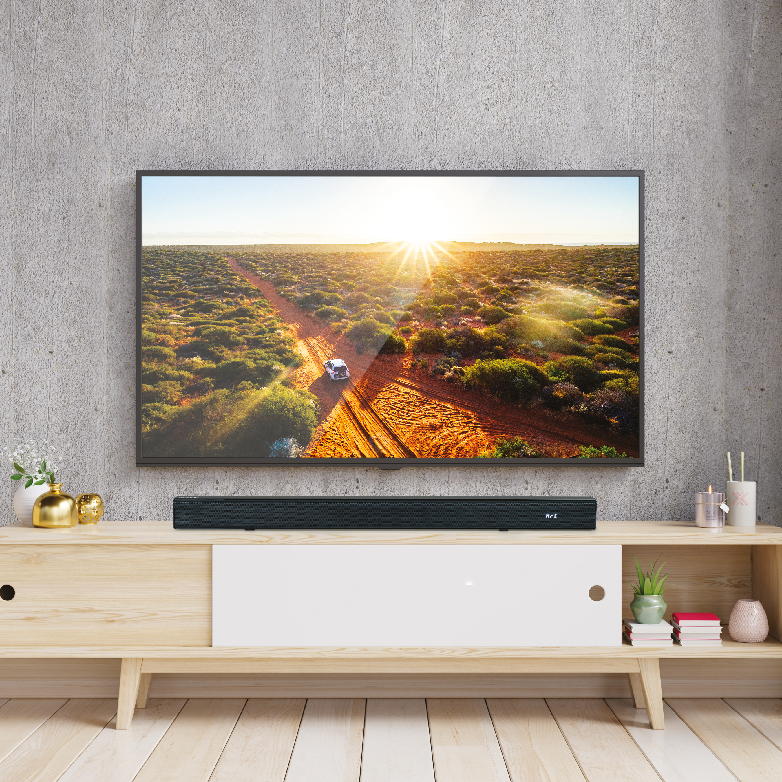 Pantalla de TV sobre un mueble de madera, una barra de sonido y un paisaje de atardecer.