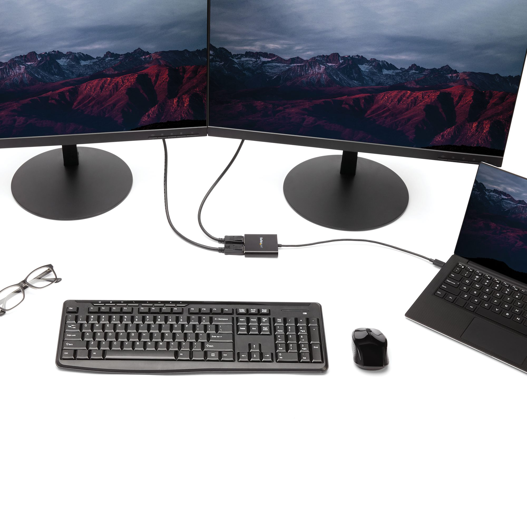Configurazione di dispositivi informatici. Due monitor, tastiera, mouse e laptop collegati a un hub.