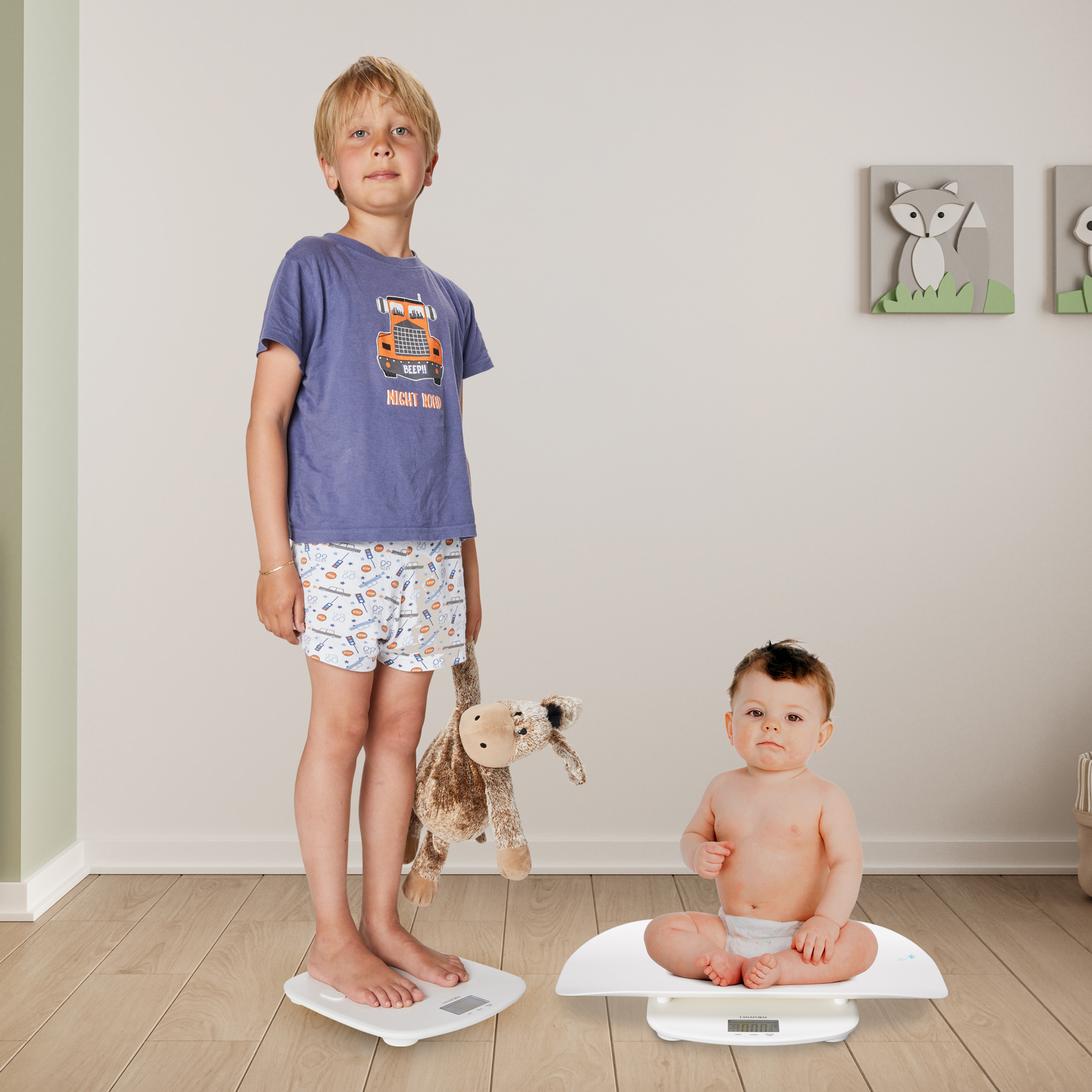 Een jongen en een baby op aparte weegschalen. De jongen staat en de baby zit.