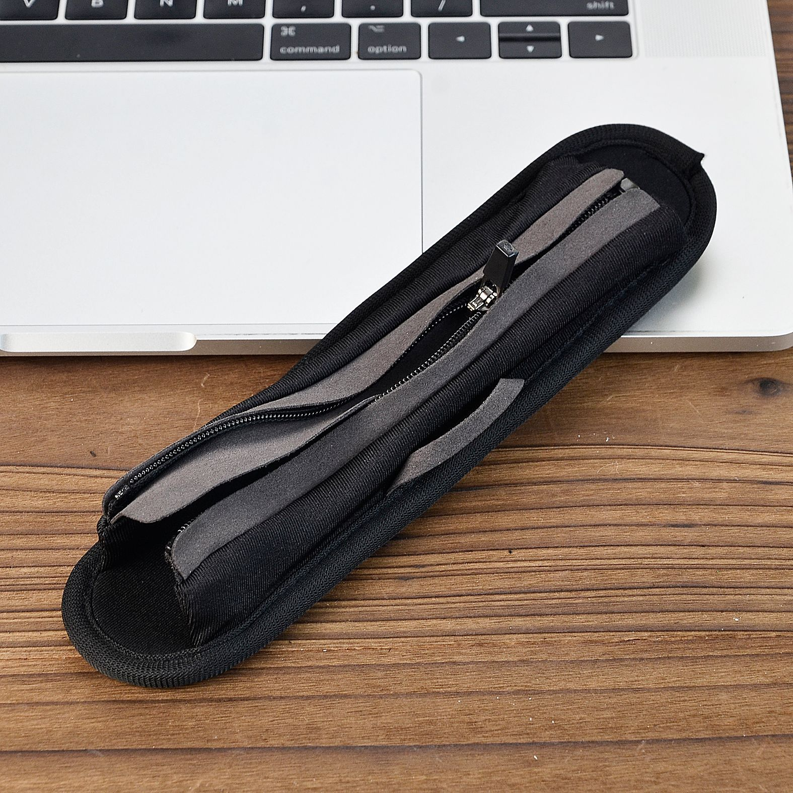 Schwarzes Federmäppchen auf einem Laptop. Der Reißverschluss ist teilweise geöffnet. Das Etui ist schwarz und grau.