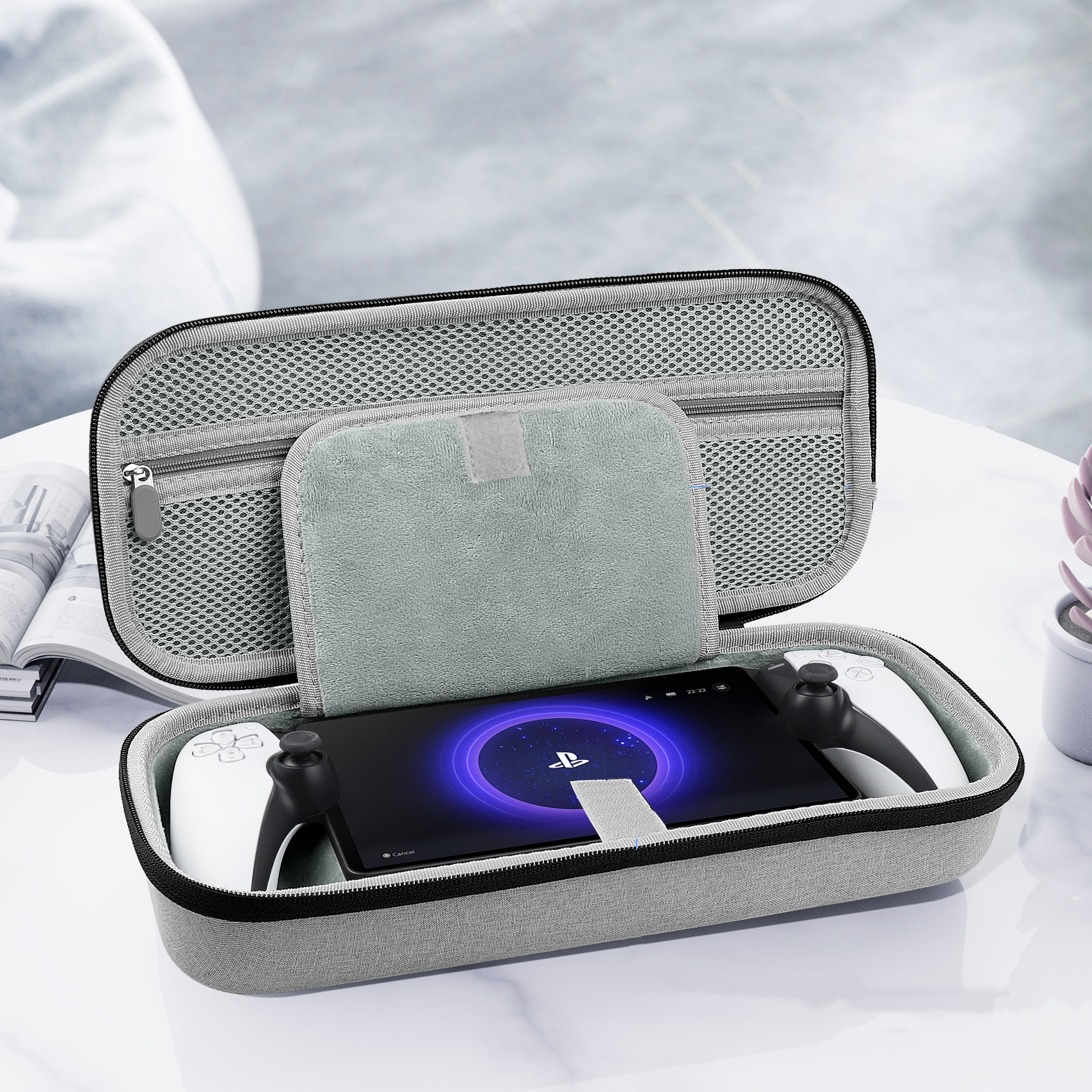 Szare etui otwarte z tabletem i kontrolerami w środku. Zapinana na zamek siatkowa góra i biały stół.