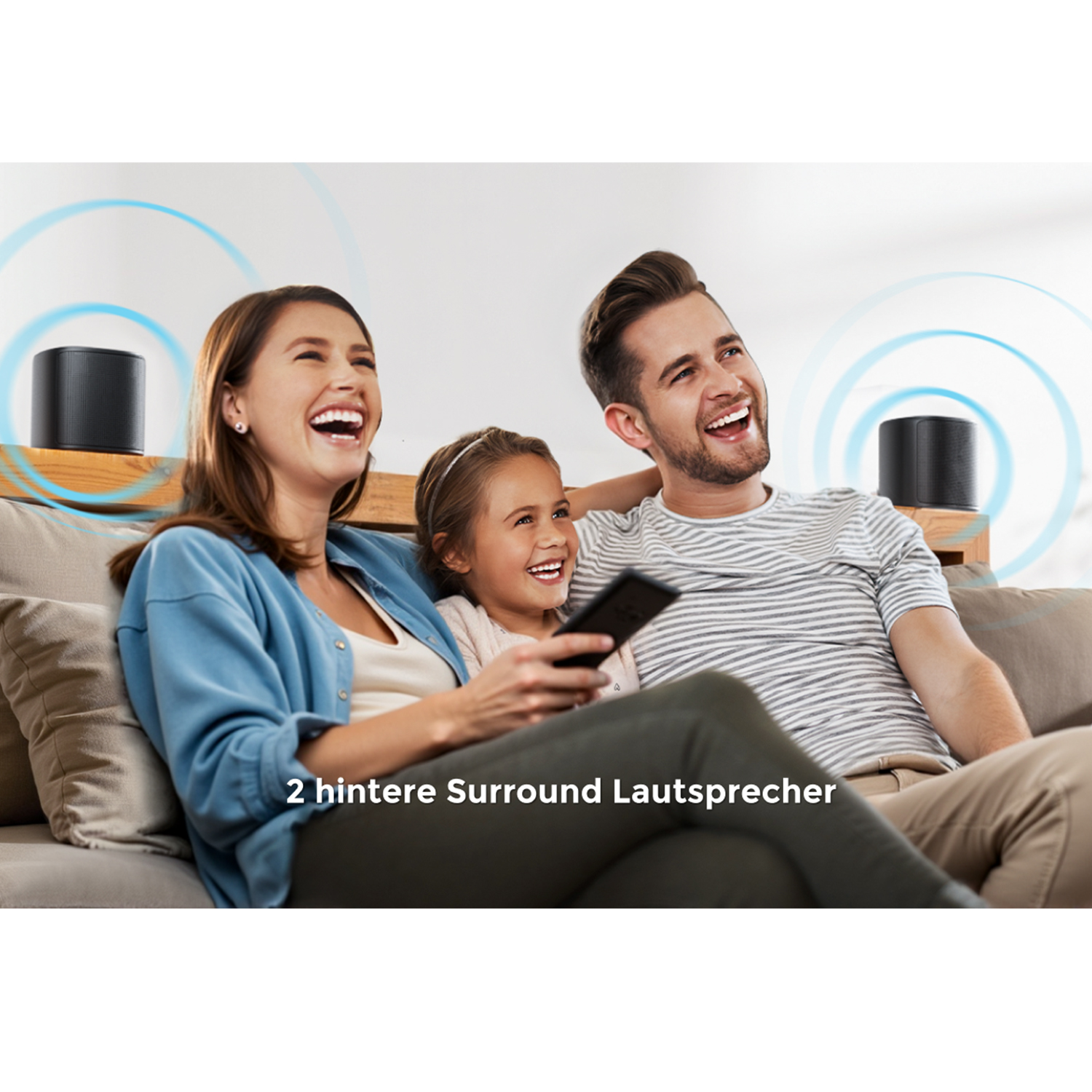 Family laughing on a sofa with two black speakers behind them. They are watching TV. White background.