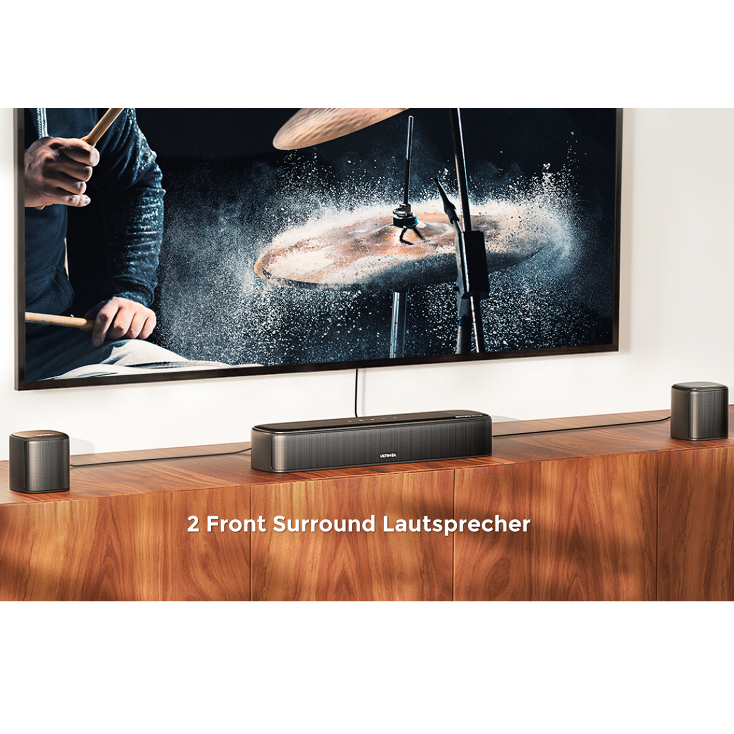 Eine Soundbar mit Fernseher, zwei Lautsprechern und Schlagzeug im Hintergrund.