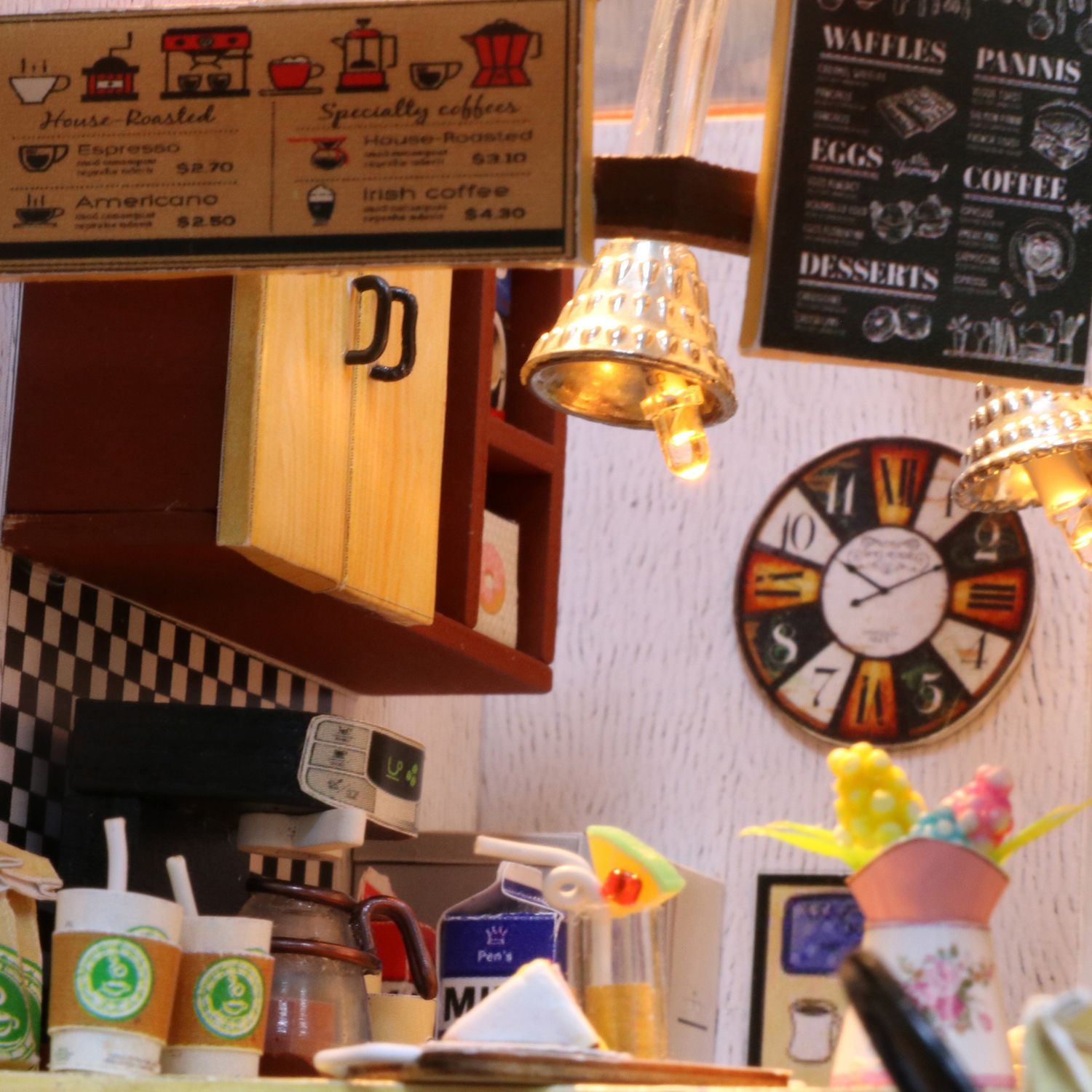 Scena di caffè in miniatura. Tavoli, sedie, macchina da caffè, orologio, menu e luci decorative.