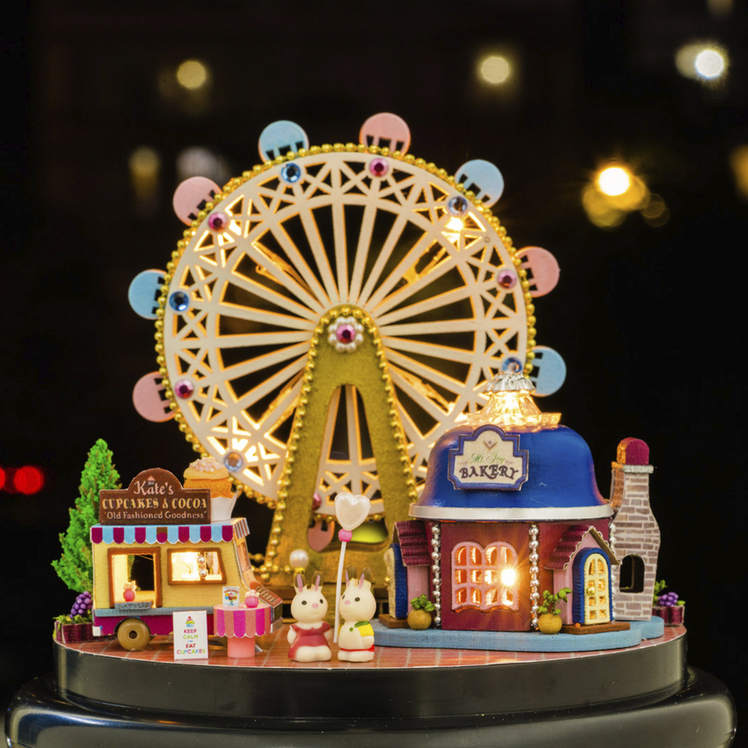 Una scena in miniatura con una ruota panoramica, panetteria, cupcake e due figure di conigli.