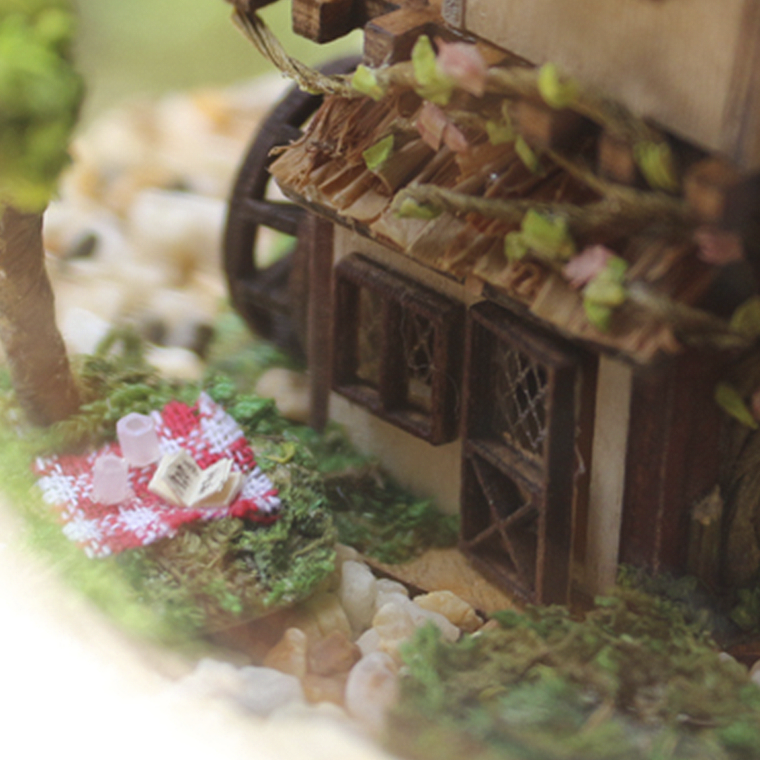 Scena in miniatura con un cestino da picnic e una casa in legno.