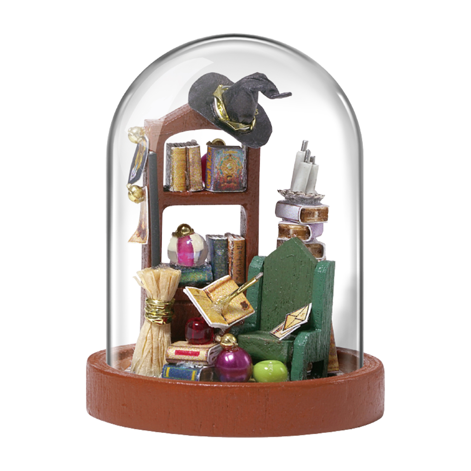 Scena in miniatura dentro una cupola di vetro con cappello da strega, libri e sedia verde.