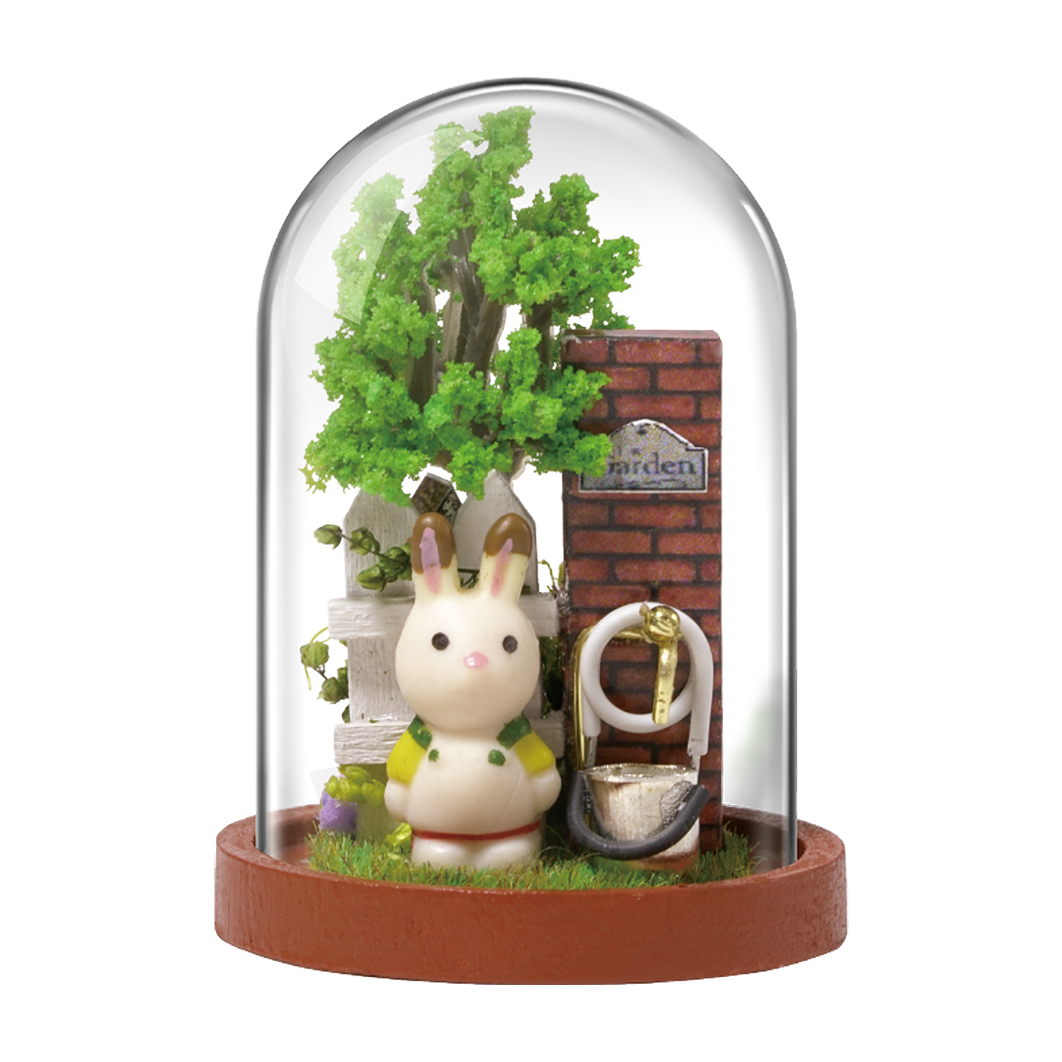 Scena in miniatura in una cupola di vetro. Figura di coniglio con recinzione e giardino. Muro di mattoni rossi e rubinetto dell'acqua.