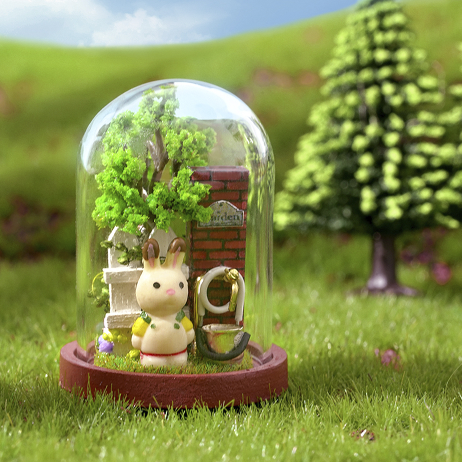 Scena di giardino in miniatura in una cupola di vetro, con coniglio e muro di mattoni.