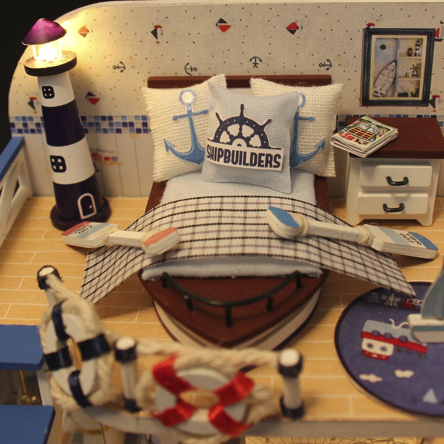 Stanza nautica in miniatura. Include un letto con cuscino, un'immagine, una lampada e oggetti nautici.