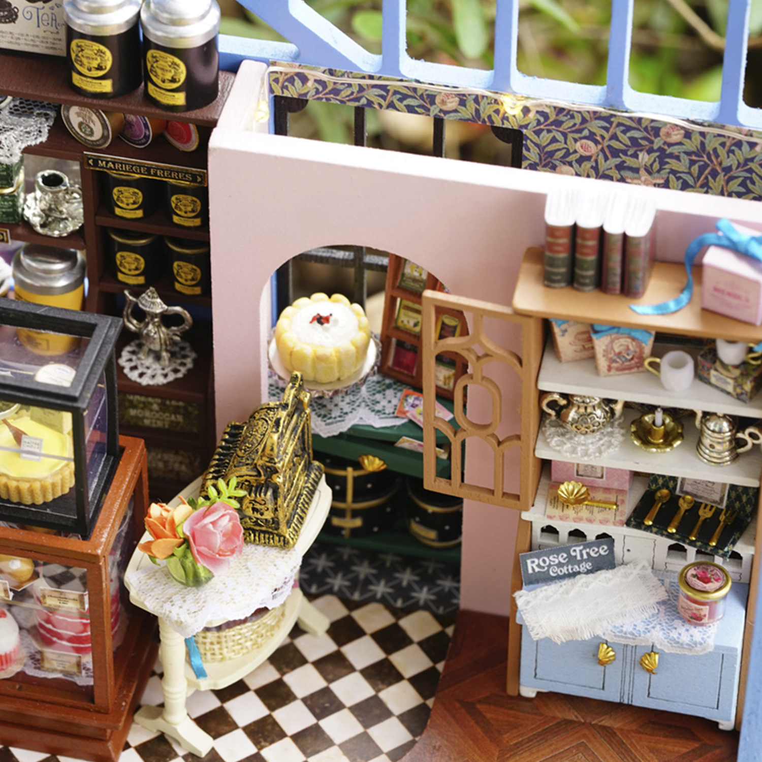 Scena di negozio in miniatura con scaffali, torte e decorazioni floreali; pavimento a scacchi.