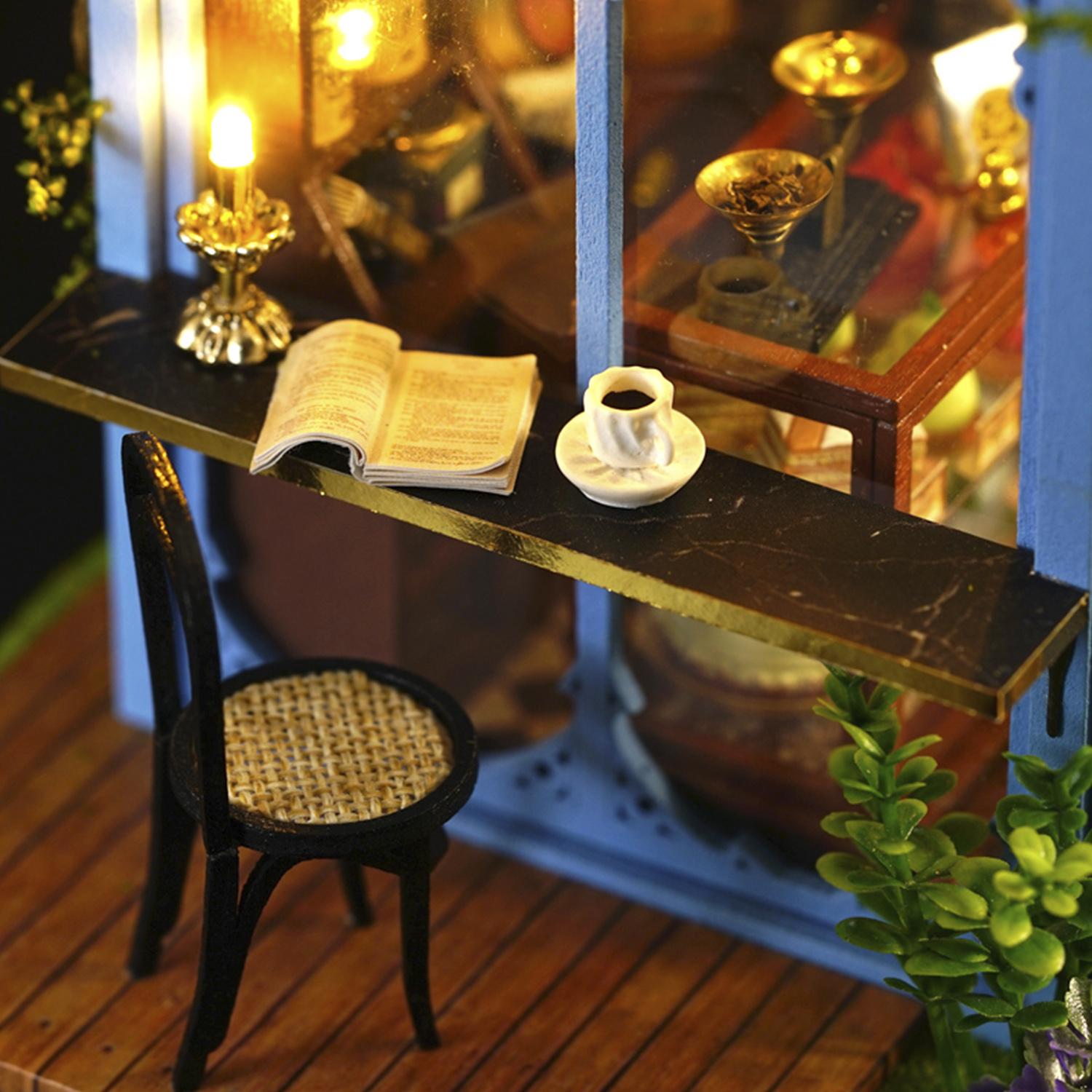 Primo piano di una scena di caffè in miniatura: tavolo con caffè, libro e candela.